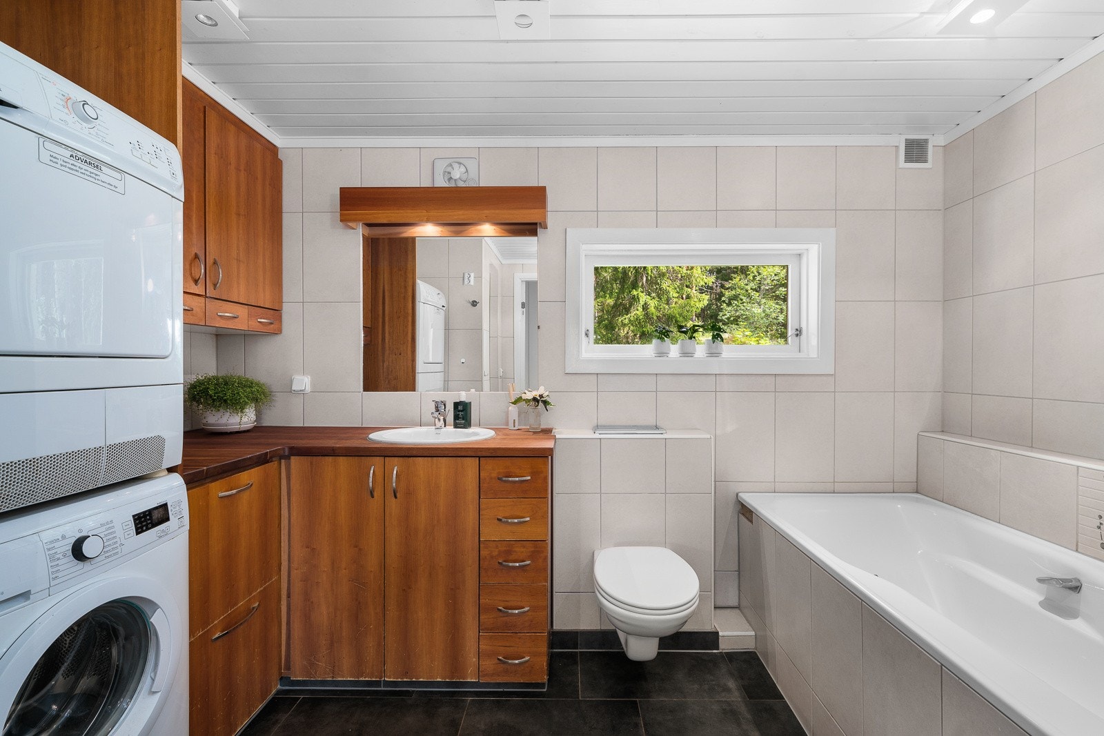 Badet har både innfliset badekar og dusjnisje med dør i glass. Videre har badet opplegg for vaskemaskin og tørketrommel i søyleløsning Galleribilde