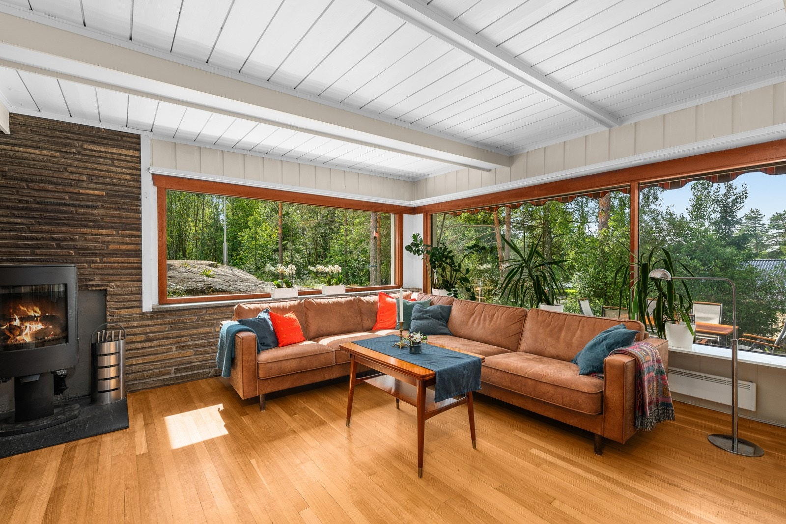 I sofasonen er det peisovn og naturstein på veggen. Ellers har stuen lysmalt panel og parkett Galleribilde