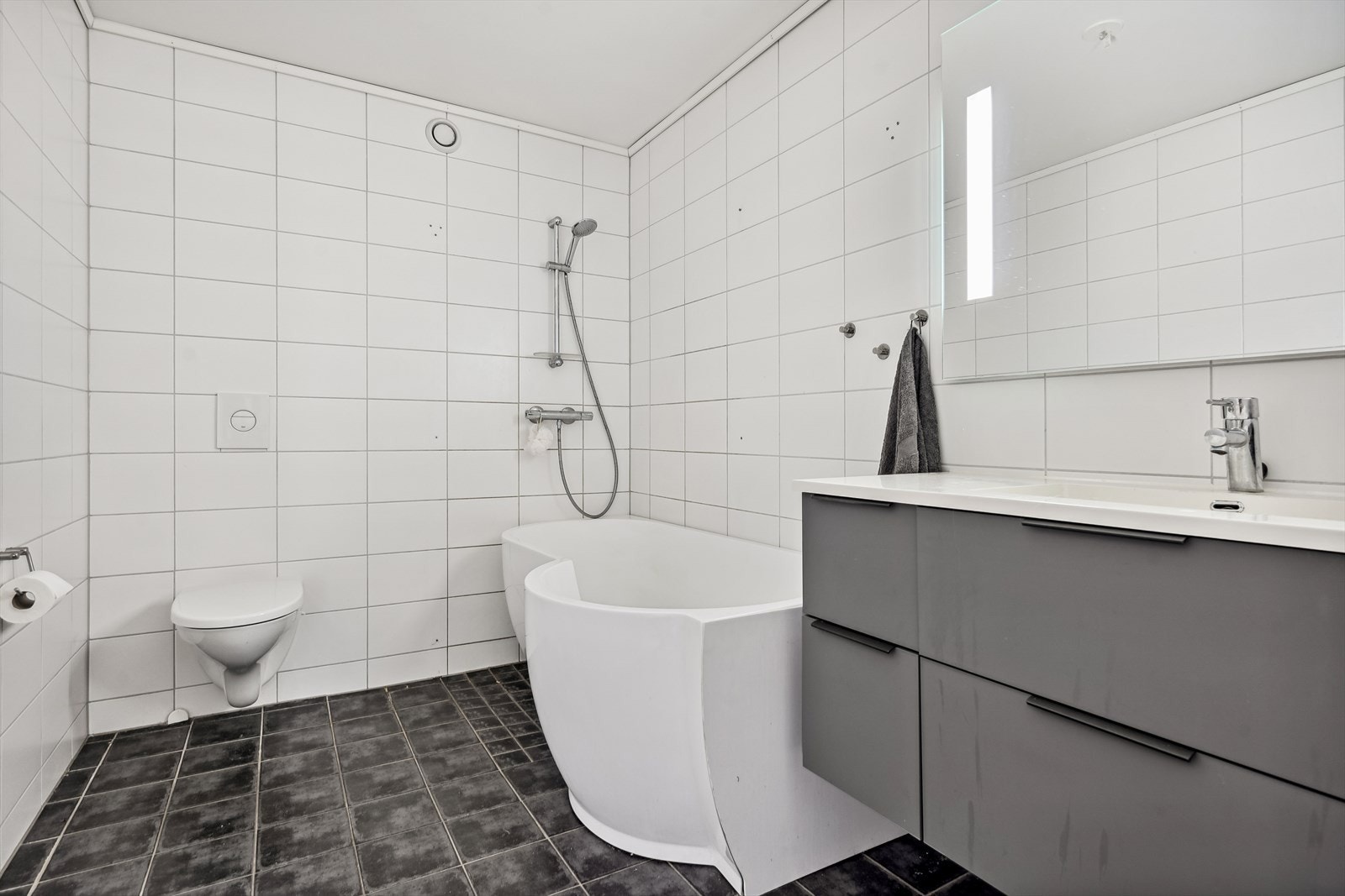 Flislagt bad med varmekabler i gulv. Her er det mulig å sette tilbake opprinnelige glassdører til dusj istedenfor badekar hvis ønskelig. Galleribilde