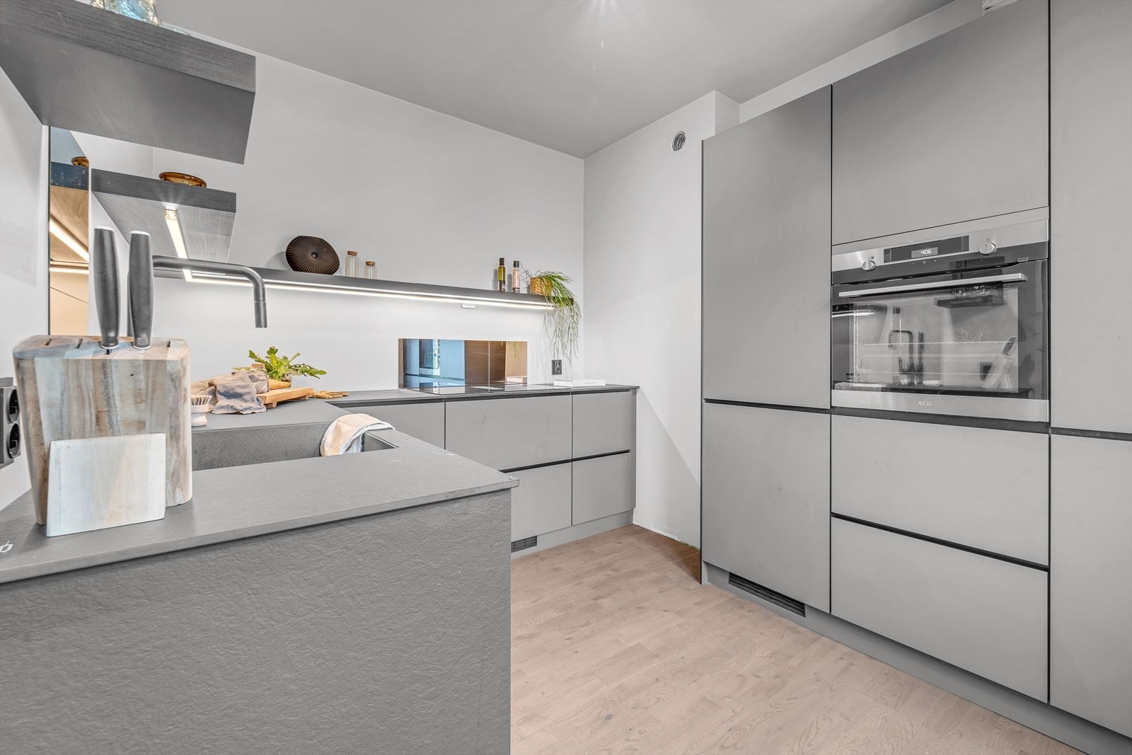 Kjøkkeninnredning med glatte fronter og kompakt laminat benkeplate Galleribilde