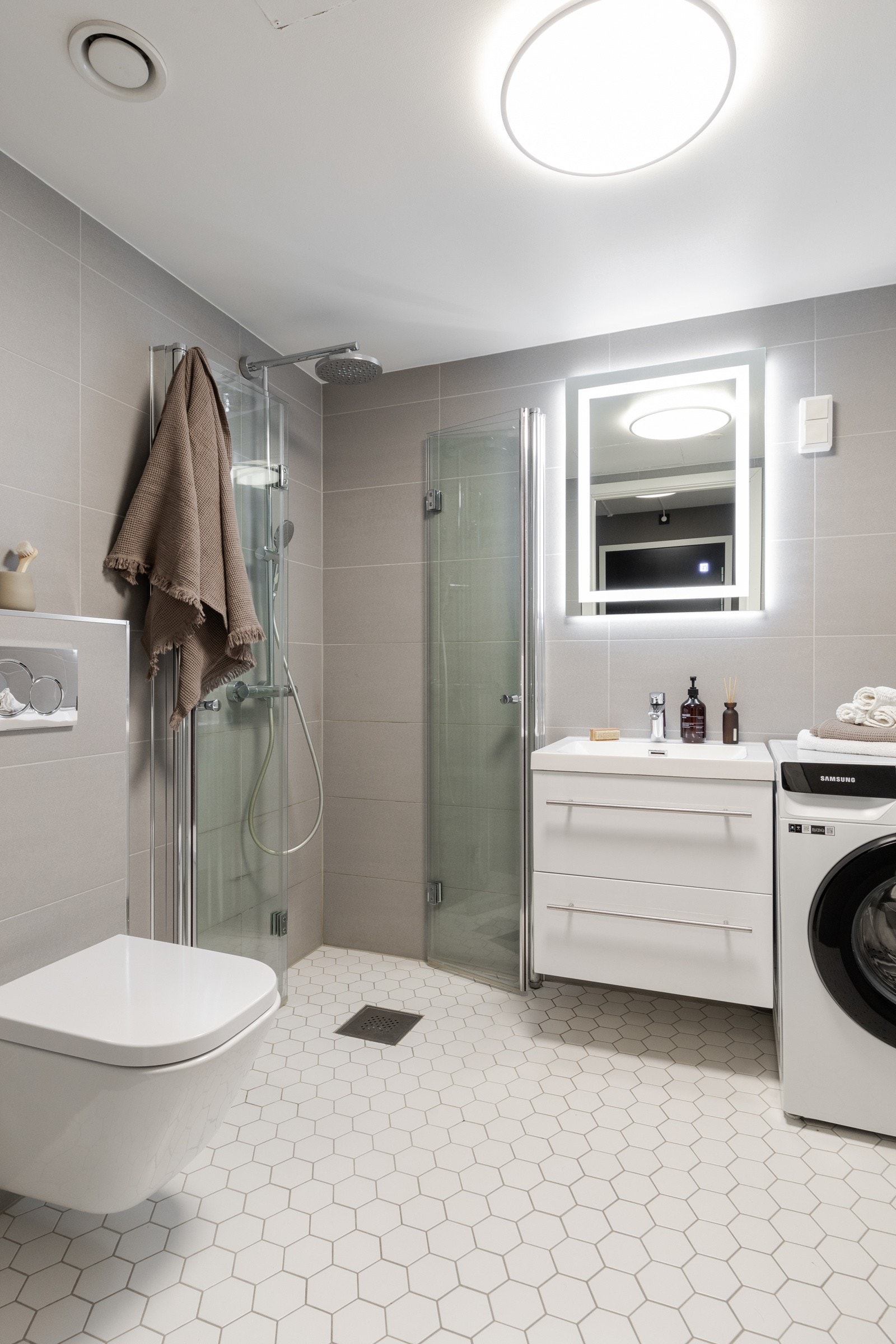 Her er det gulvvarme, vegghengt toalett, romslig dusjhjørne med pene glassdører og opplegg for vaskemaskin Galleribilde