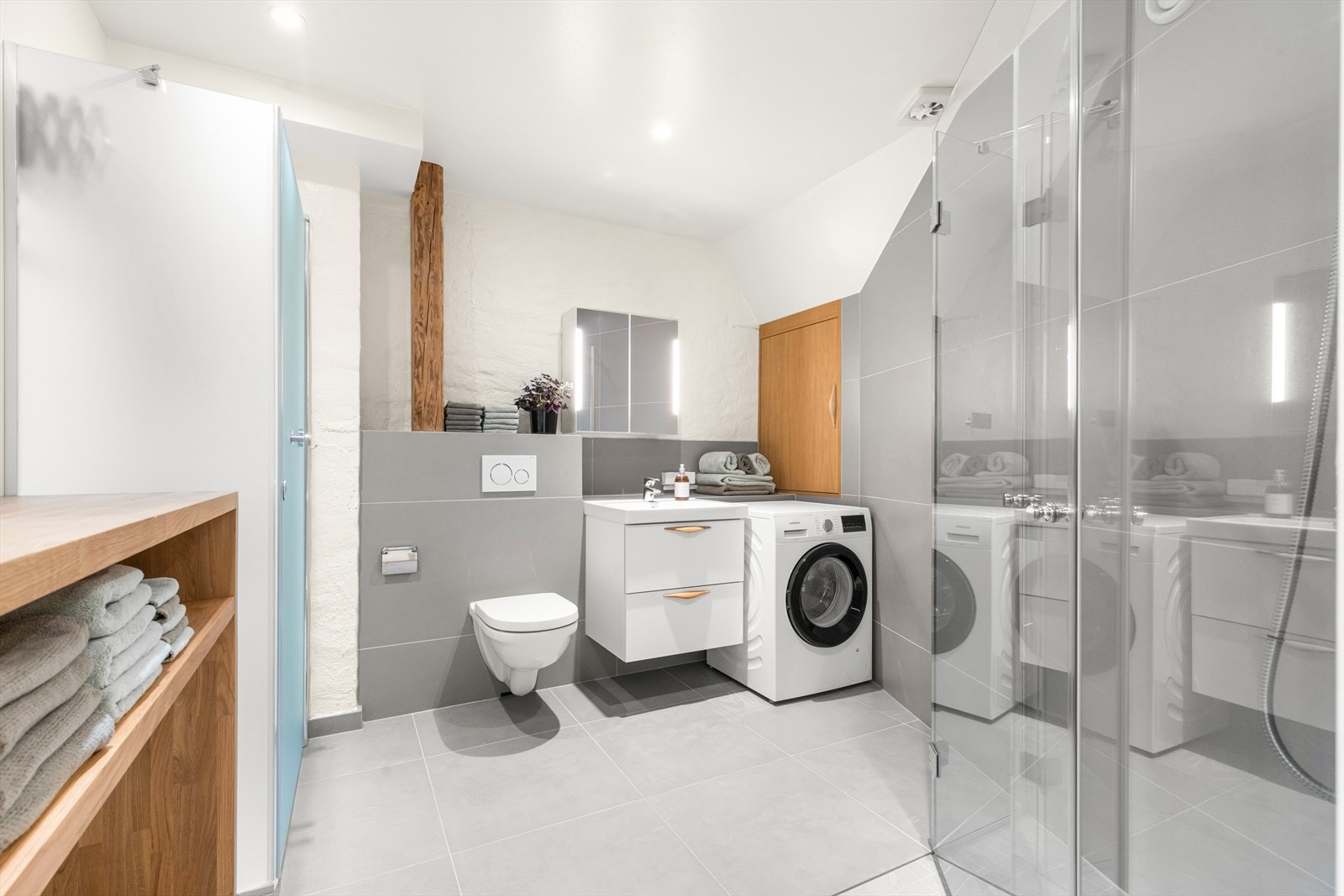 Badet har store italienske keramiske fliser av typen Cæsar More Manhattan 120x60 cm og 60x60 cm. Den store dusjen er spesialbygget med glassvegg og glassdører fra Glassmester Espen Moe. Dette er klart, herdet sikkerhetsglass med polerte kanter. Galleribilde