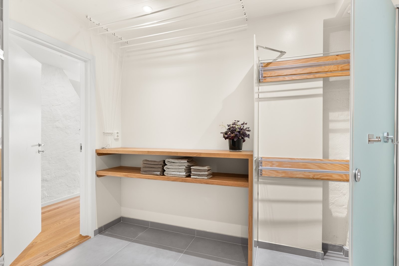 Det er plassbygde tørkeløsninger slik at en slipper løse tørkestativ slengende rundt i huset. Dette flotte store baderommet/vaskerommet har spesialbygget innglasset tørkenisje og et romslig takhengt tørkestativ. Galleribilde