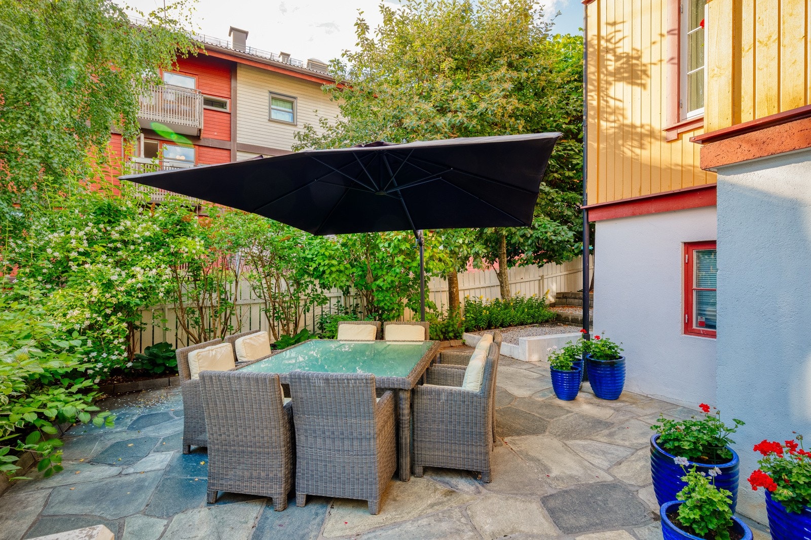 Sameiet har flotte fasiliteter. Blant annet denne skiferbelagte uteplassen med stort spisebord og plass til 8 personer og grill. Galleribilde