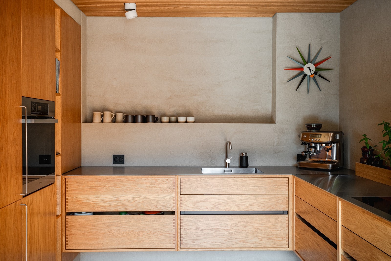 Kjøkkenet har eikefronter og benkeplater i rustfritt stål. Armatur fra Vola. Vegghengte benkeskap. Skreddersydde løsninger. Dimbare spotter i to soner. Galleribilde