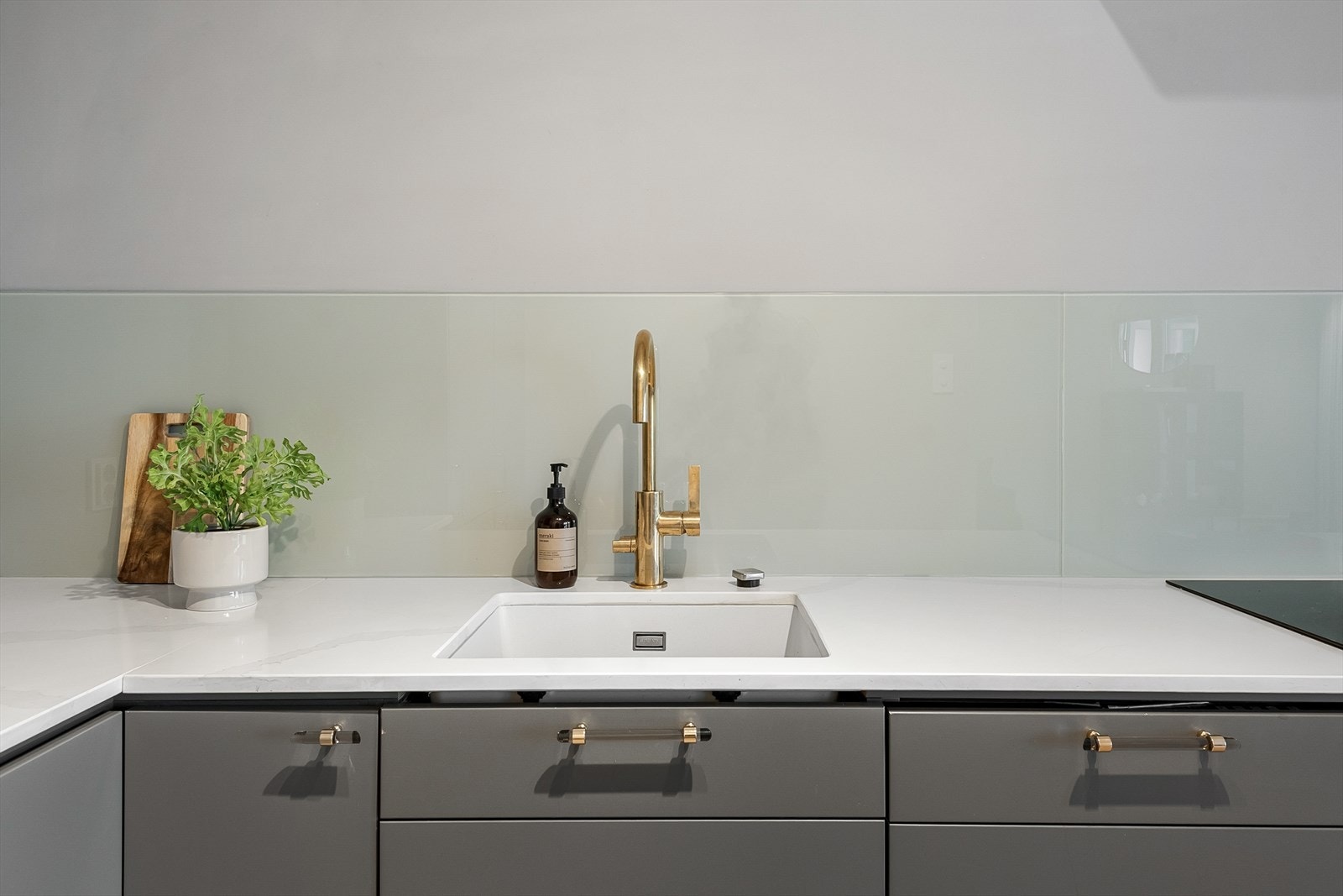 Benkeplate i kompositt med underlimt oppvaskkum og blandebatteri i messing. Galleribilde