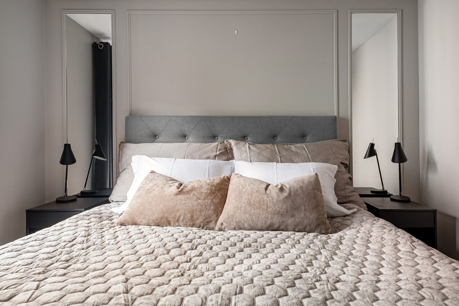 Smakfulle detaljer på vegg med dekorlister og innrammede helspeil på hver side av sengen. Galleribilde