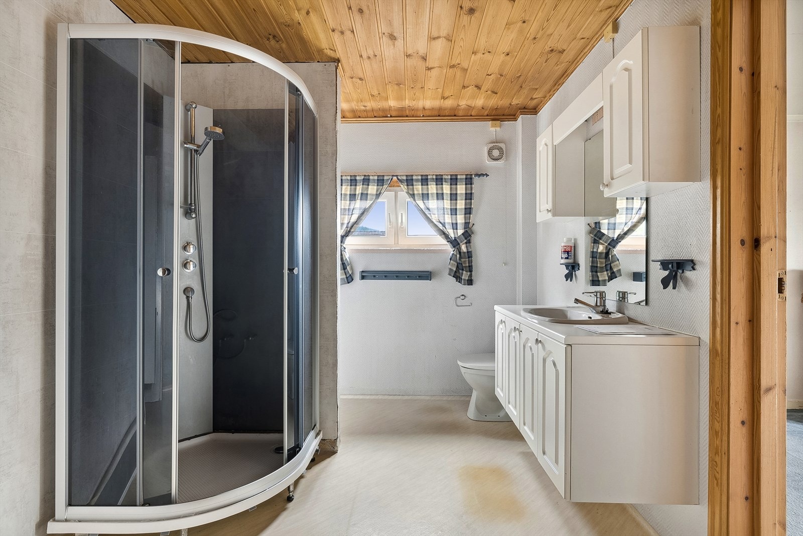 Baderom utstyrt med servant nedfelt i skapinnredning, dusjkabinett og wc. Galleribilde