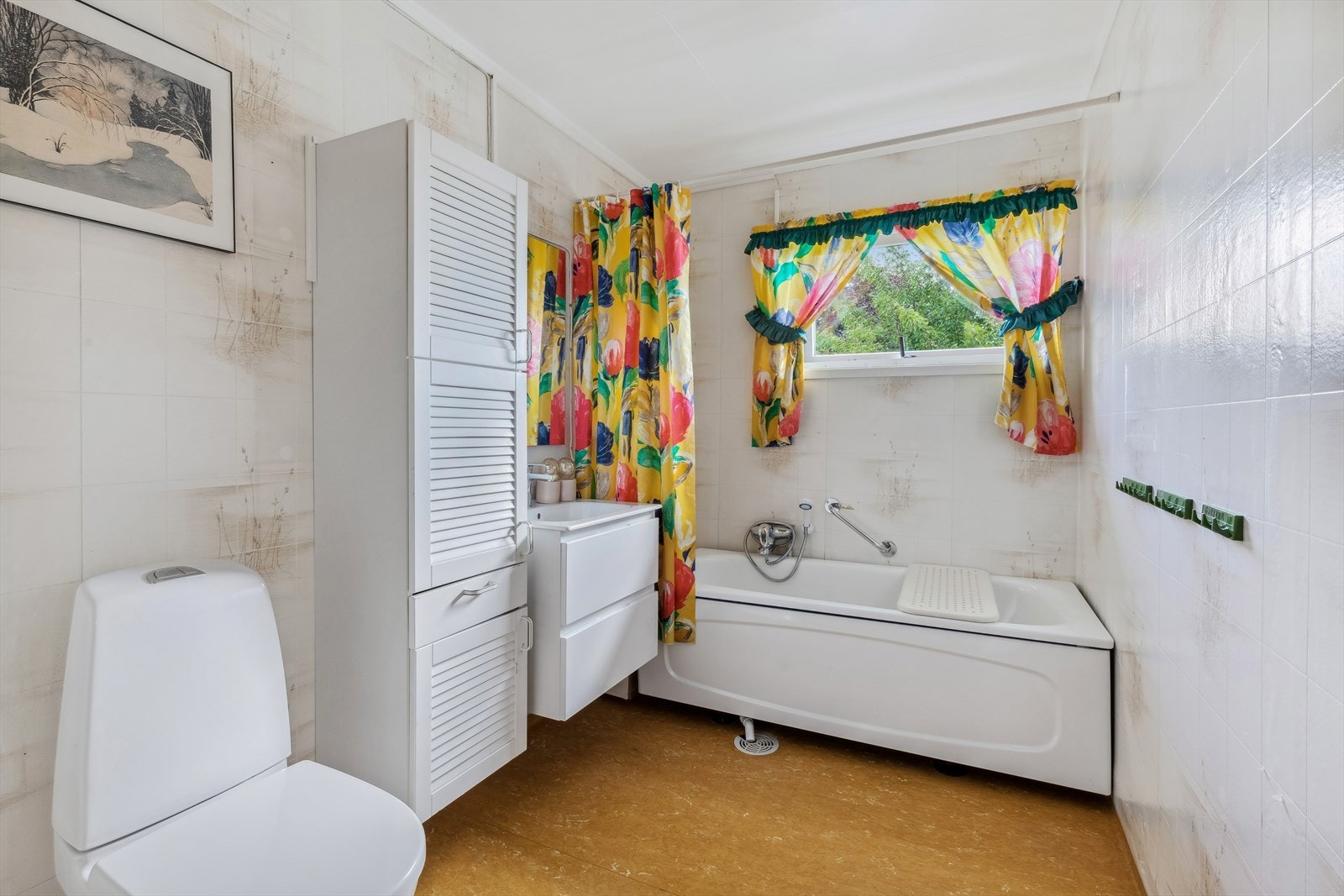 Funksjonelt bad med belegg på gulv og våtromstapet på vegger. Badet her er utstyrt med badekar med forheng samt nymontert gulvstående wc og servantinnredning med skuffer Galleribilde