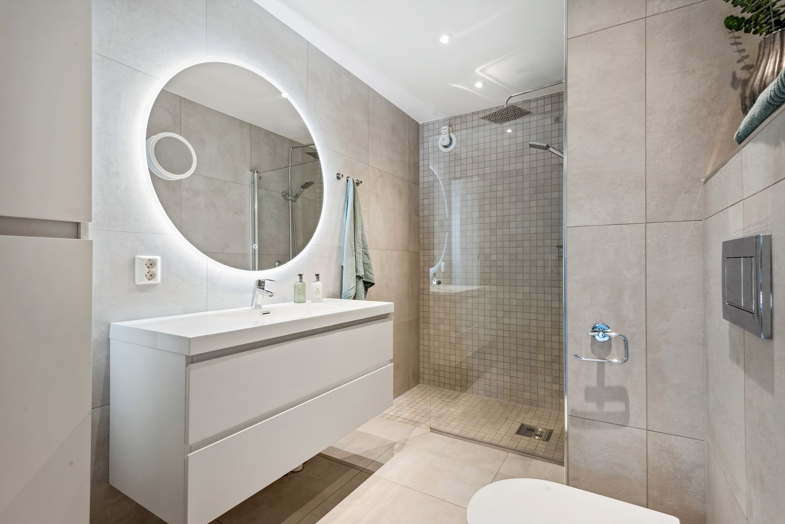 Badet inneholder baderomsinnredning med servant, speil med belysning, høyskap, dusjnisje og veggmonter wc. Galleribilde