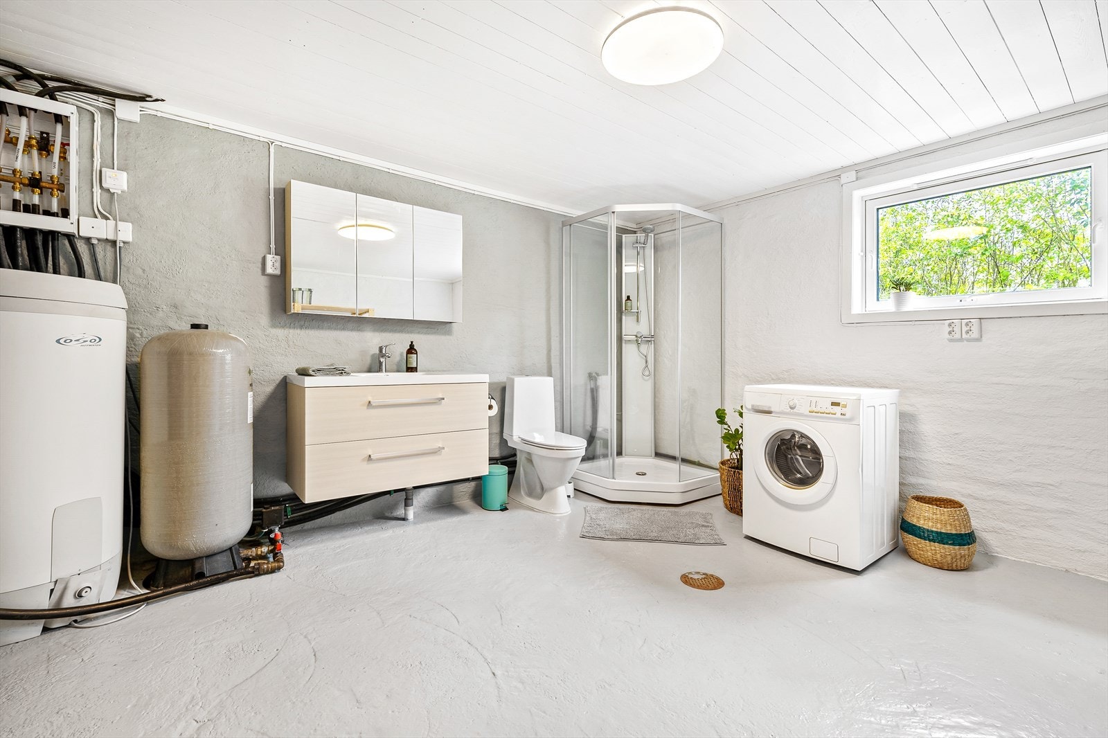 Vaskerom/bad innredet med dusjkabinett, heldekkende servant på skuffeinnredning, samt plass for vaskemaskin Galleribilde