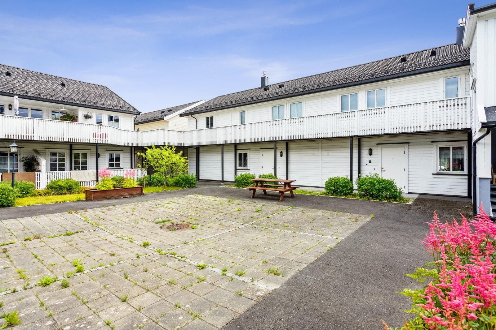 Pent opparbeidet fellesareal med benker og planter. Galleribilde