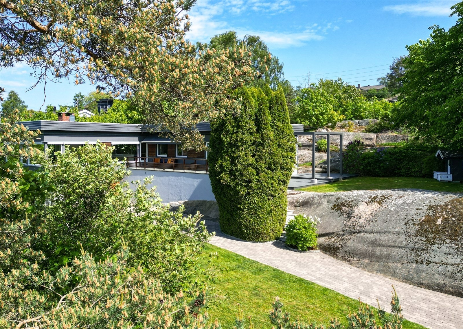 Rundt om finner du pent formede einerbusker, roser, villvin og rododendron i flere farger og varierte prydbusker. Galleribilde