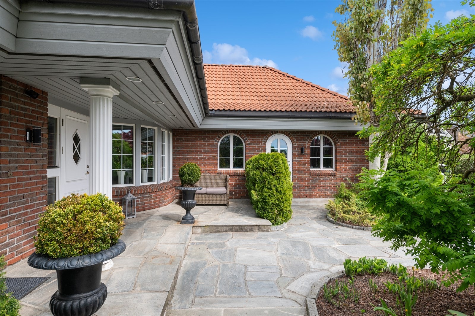 Tomten er parkmessig opparbeidet med skiferbelagte gangbaner og granitt kantstein, samt flott beplantet med ulike prydbusker, plen, trær og stedvis naturtomt. Galleribilde