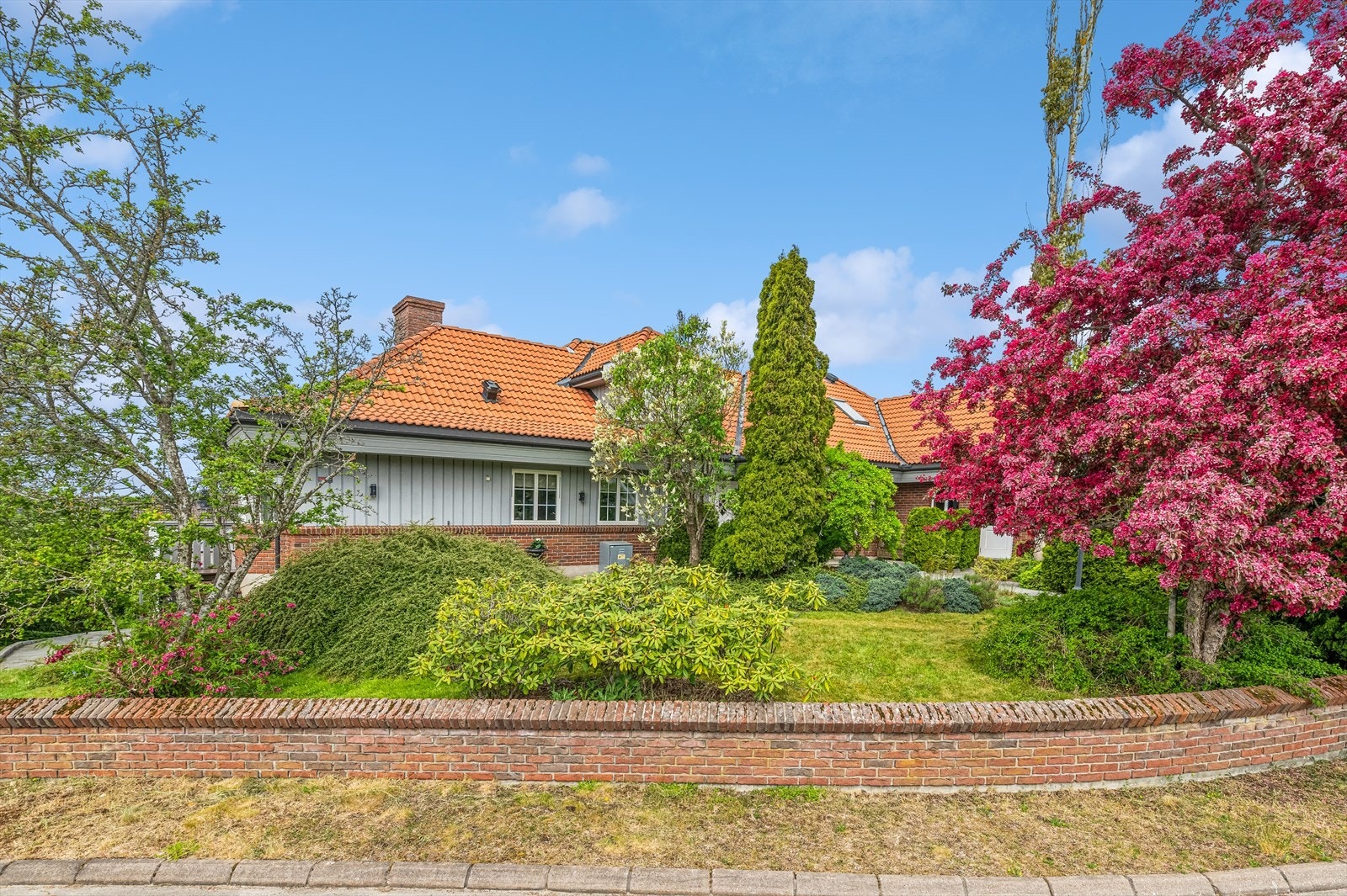 Mot veien er eiendommen avgrenset med teglsteinsmur og foran garasjen er det stor gårdsplass med belegningsstein. Galleribilde