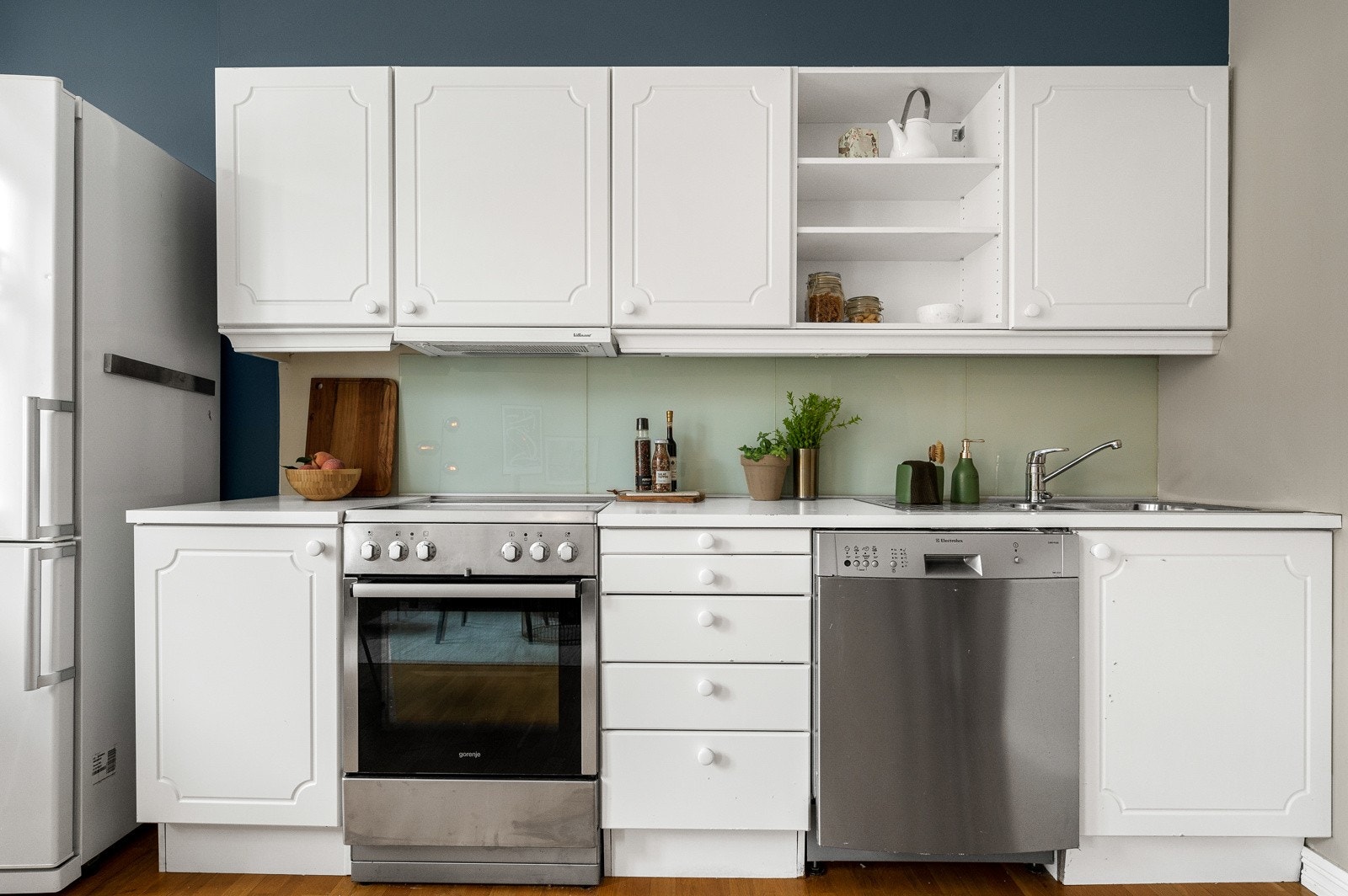 Kjøkkenet er i åpen løsning mot stuen, hvor du har kjøkkeninnredning med malte profilerte fronter, laminat benkeplate, plater over benk og belysning i overskap. Galleribilde