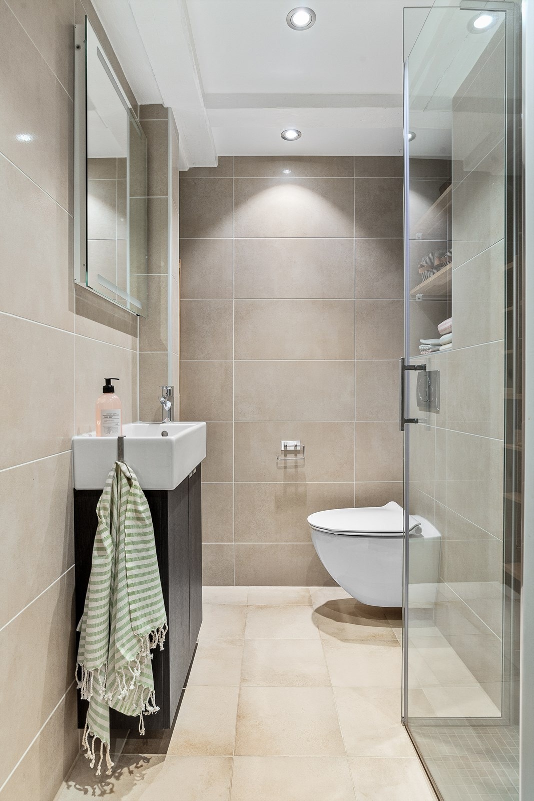 Lyst baderom med gulvvarme, vegghengt wc, foldedører i glass og servant med underskap. Opplyses fra tidligere eier å være fra 2015. Galleribilde