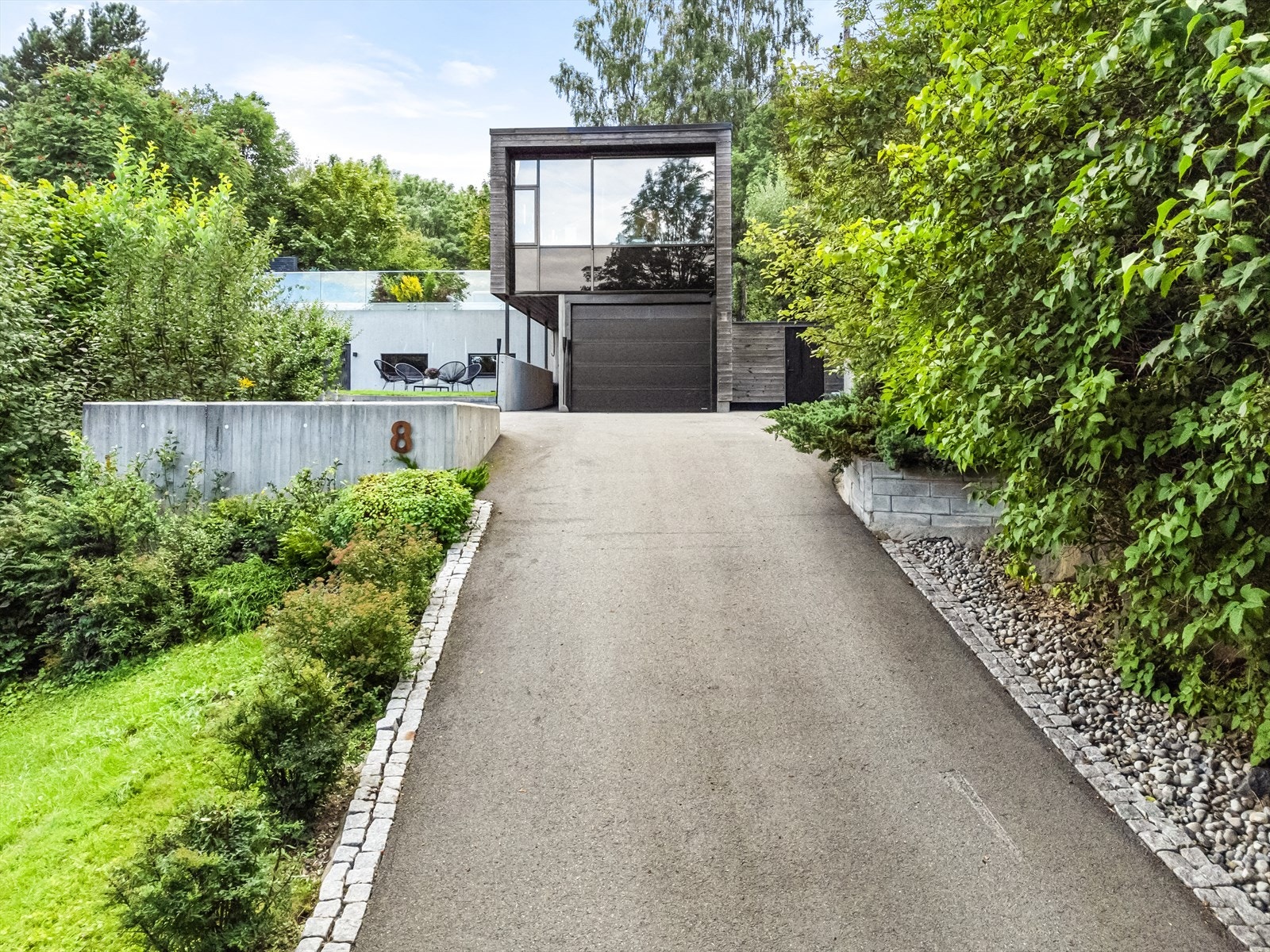 Eiendommens uteområder er pent opparbeidet med støttemurer, belysning og asfaltert innkjørsel Galleribilde