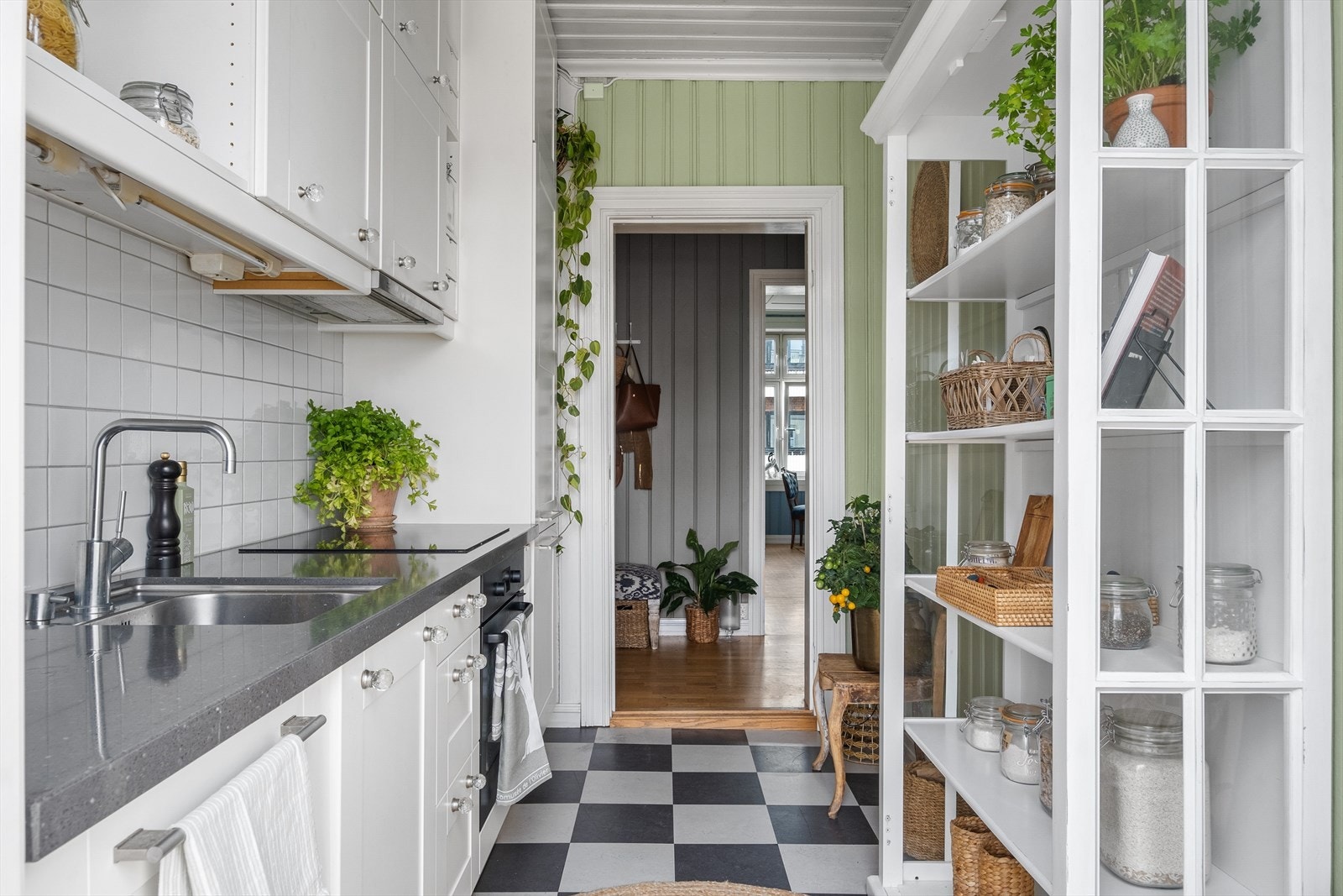 Innredning fra 2015 med profilerte fronter, flis på vegg over benkeplaten og benkeplate i stein. Det er integrerte hvitevarer med kjøl/fryseskap, oppvaskmaskin, stekeovn og platetopp med kullfiltervifte Galleribilde