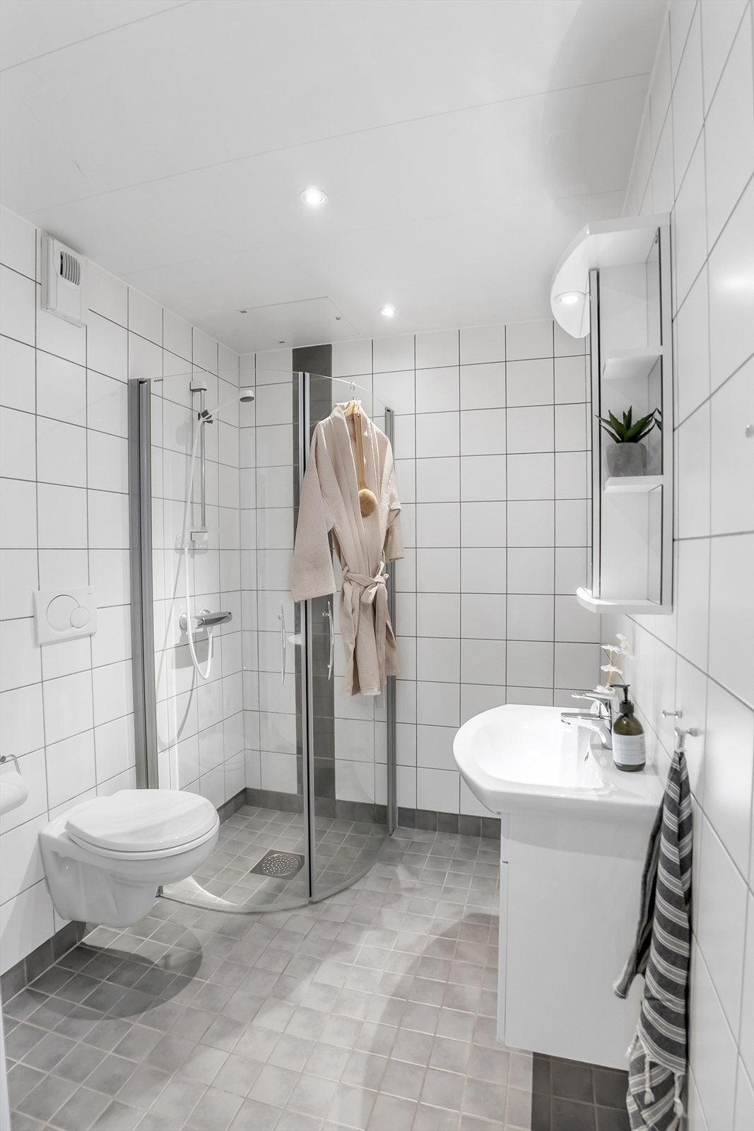 Lyst og romslig flislagt baderom med elektriske varmekabler og innfelte downlights. Galleribilde