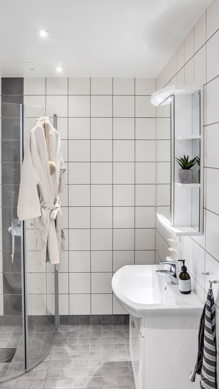 Badet er innredet med vegghengt klosett, servantinnredning, servant med ettgreps blandebatteri, dusjdører, dusjarmatur, opplegg og plass til vaskemaskin. Galleribilde