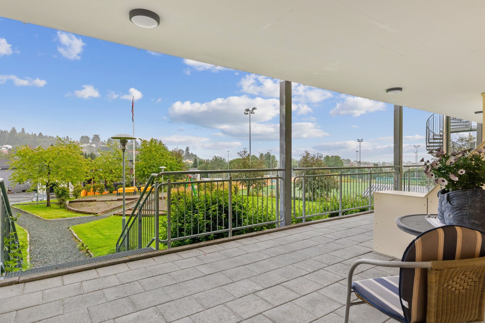 God plass til cafebord på svalgangen ved inngangsdøren. Her er det fin utsikt mot fellesområder og formiddagssol. Galleribilde