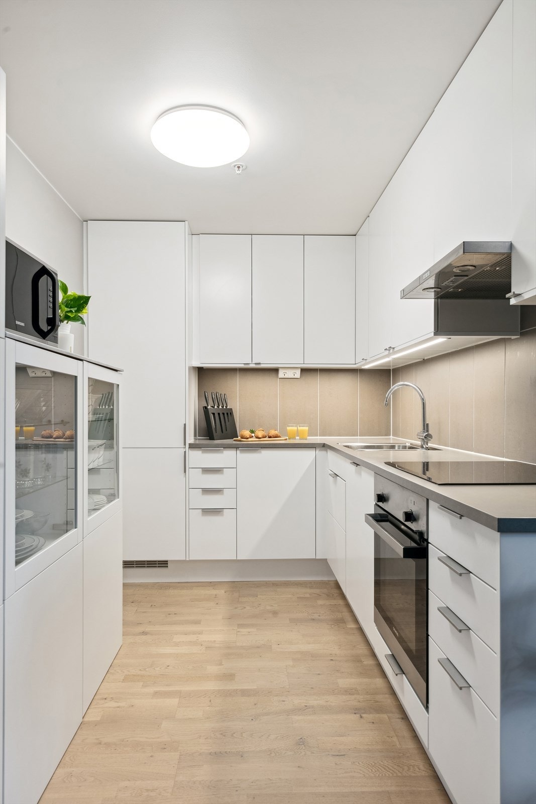Kjøkkeninnredningen består av benke- og overskap med slette fronter, benkeplate av laminat og fliser på vegg over benk. Videre er kjøkkenet utstyrt med integrert platetopp, komfyr, oppvaskmaskin og kjøl/frys Galleribilde