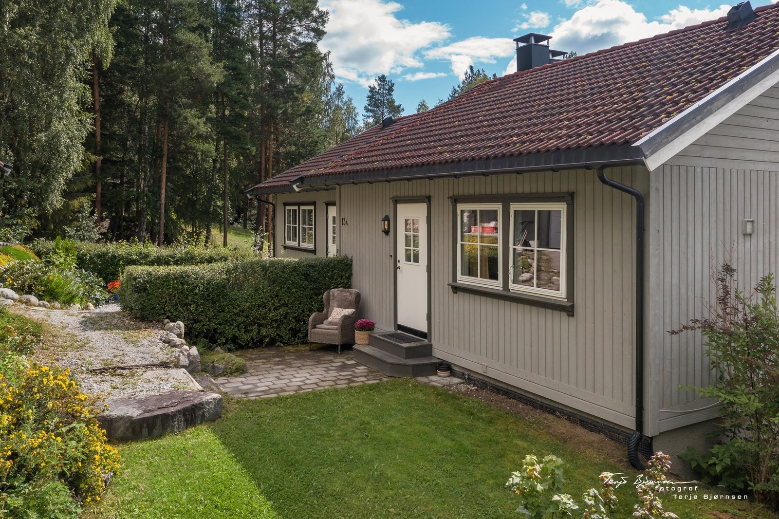Pent opparbeidet inngangsparti med gressplen og hekk. Galleribilde