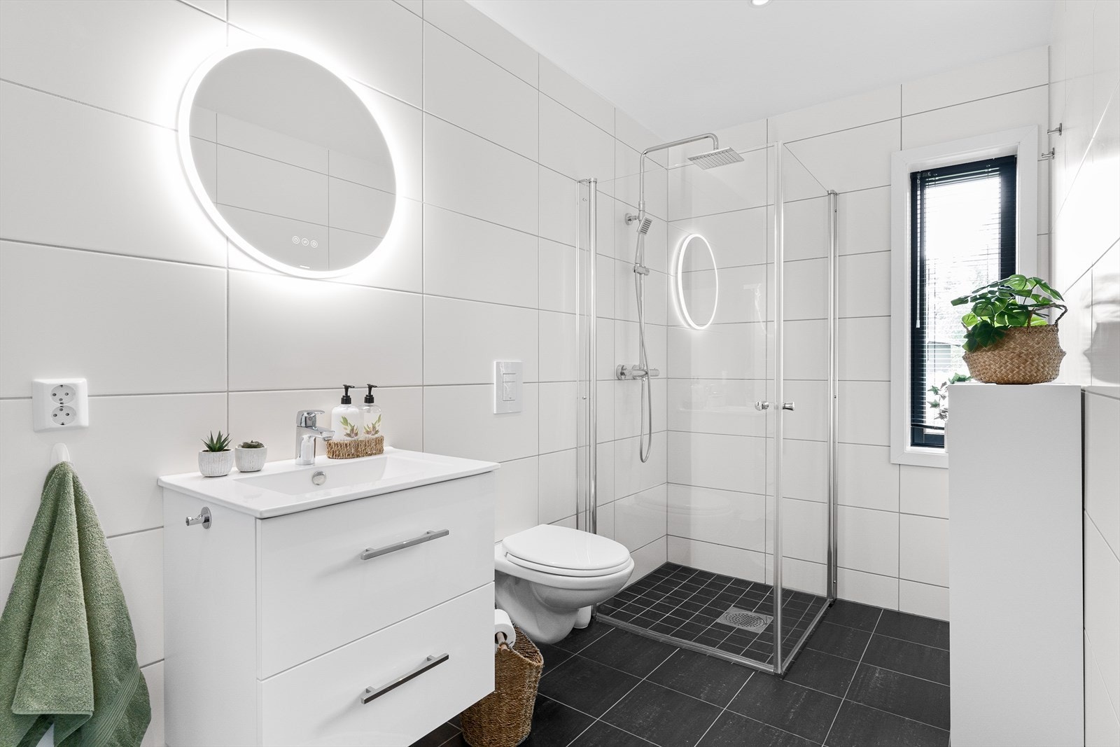 Badet nede i hovedplanet. Flislagt, med WC og dusjhjørne. Servant med skuffinnredning, og overspeil med integrert og dimbar belysning. Galleribilde