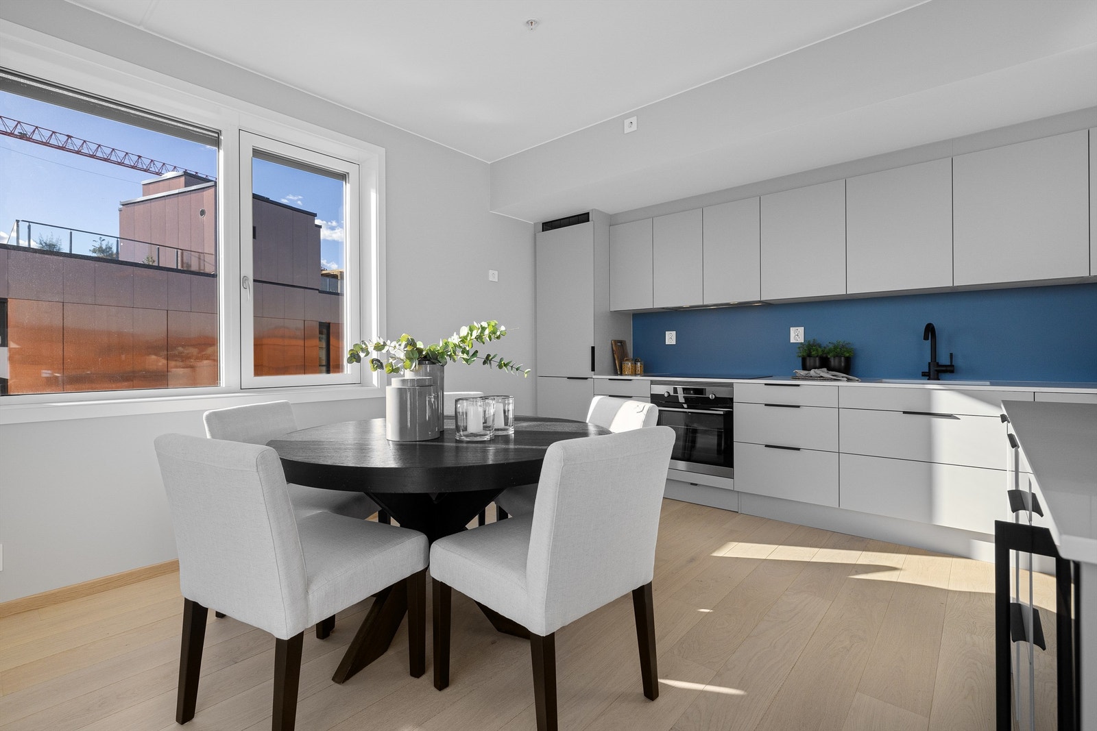 Integrerte kvalitetshvitevarer fra AEG i form av induksjonsplatetopp, oppvaskmaskin, kombiskap og stekeovn i rustfritt stål. Vinskap montert i kjøkkenøy Galleribilde