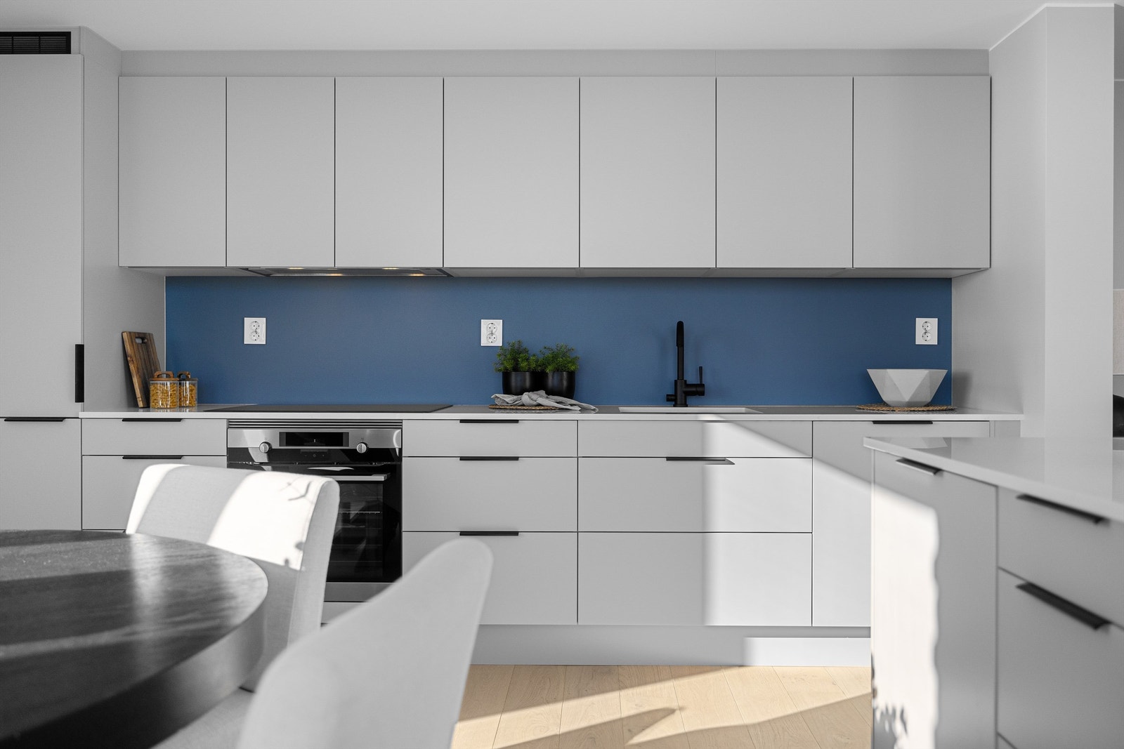 Lekker og moderne kjøkkeninnredning fra HTH med slette lyse fronter og benkeplate i stein Galleribilde