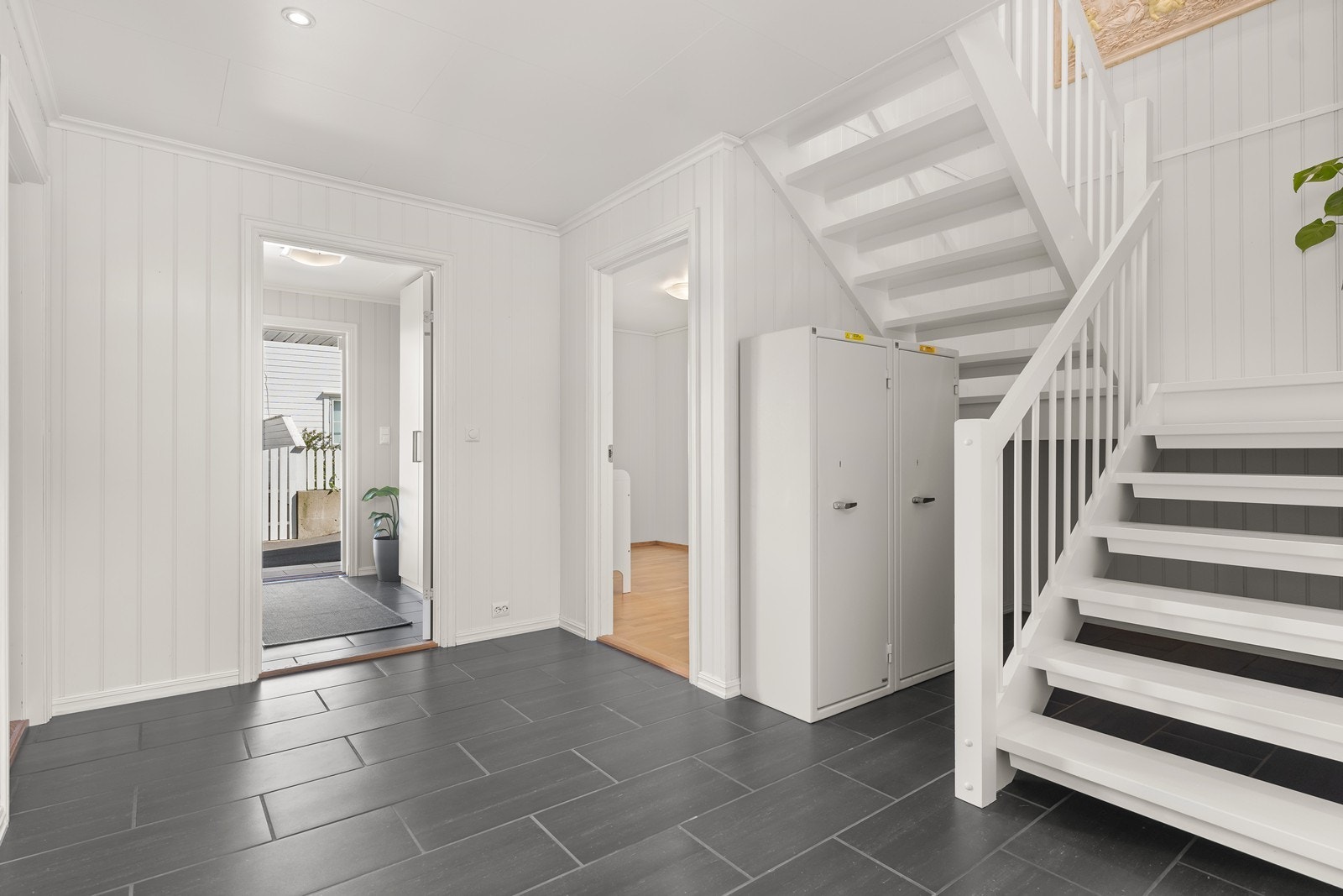 Yttergang har fliser og varmekabler. Hallen med trapp opp til 2. etasje har også fliser. Fra hallen er det utgang til fremsiden av huset, samt dør inn til alle 3 soverommene, bad og vaskerom. Galleribilde