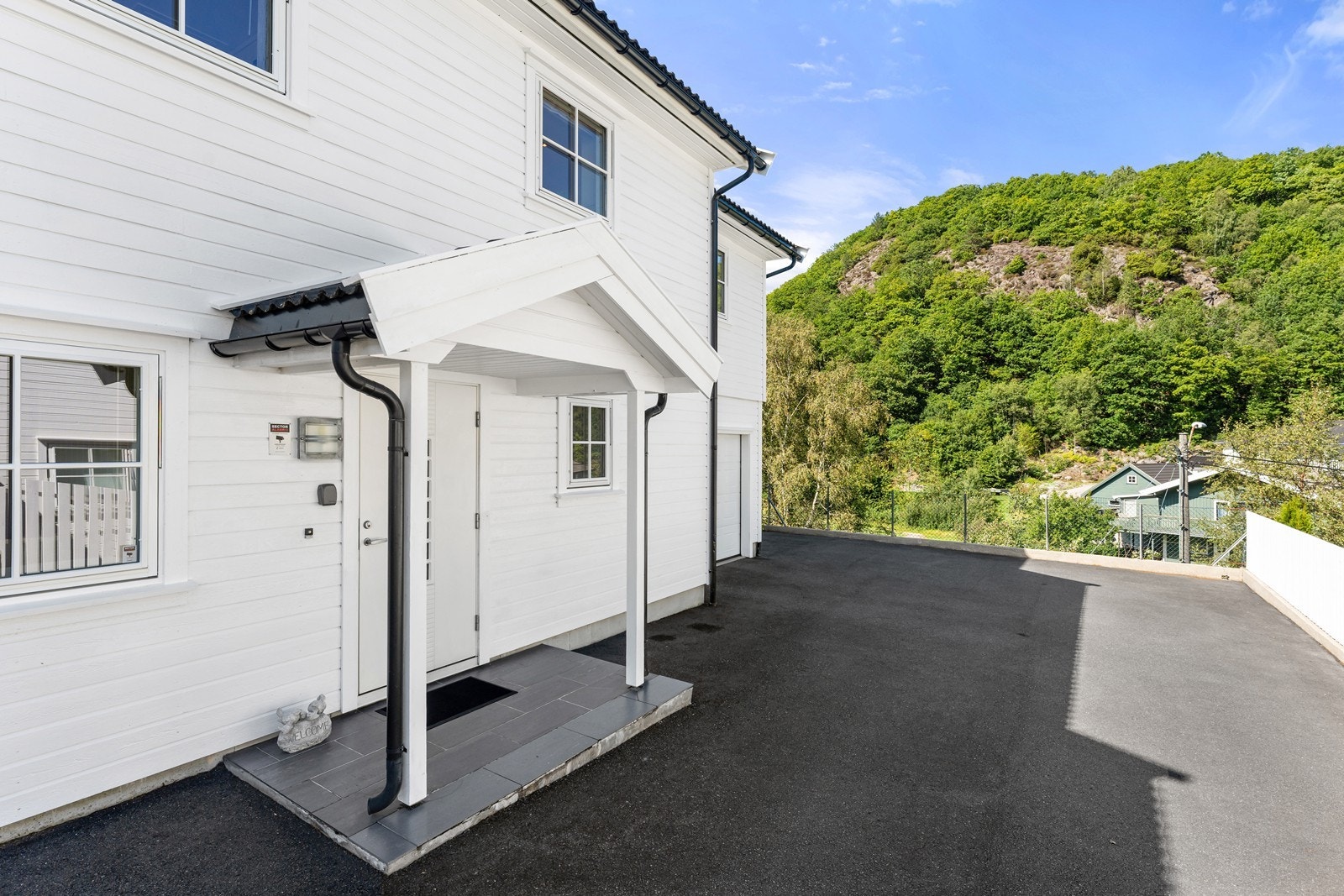 Gårdsplass er asfaltert og det er plen på fremsiden av boligen. Galleribilde
