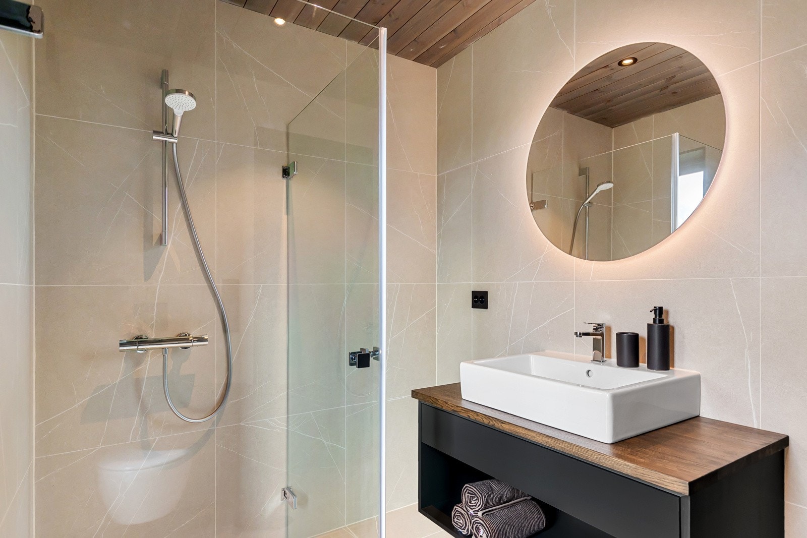 Badet har dusjhjørne, innredning med servant og veggmontert toalett. I tillegg er det varmekabler i gulv. Galleribilde