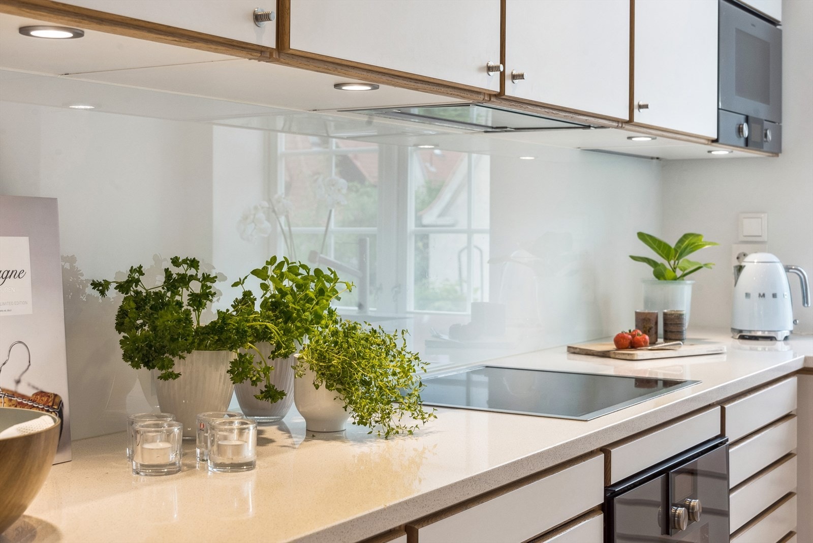 Det er montert downlights under overskapene på kjøkkenet, glassplate på vegg over koketopp, samt kompositt benkeplate. Galleribilde