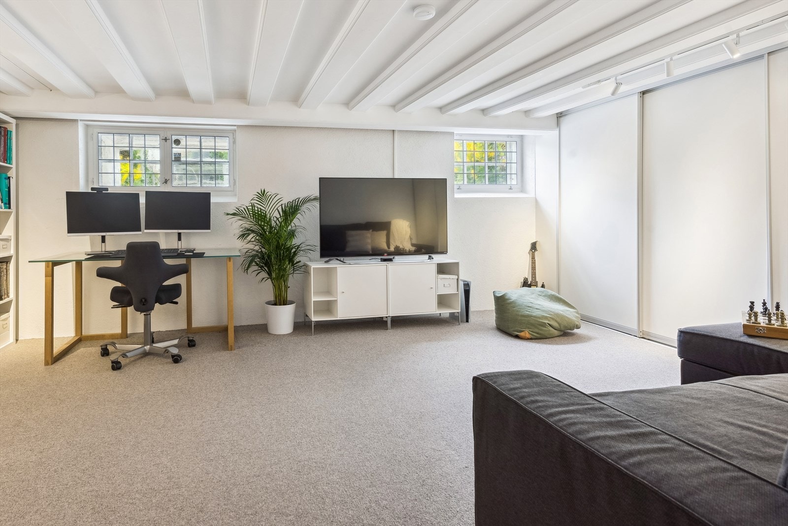 Kjellerstuen har god plass til hyggelig TV-krok, kontorplass, bokhyller og skyvedørs-oppbevaring Galleribilde