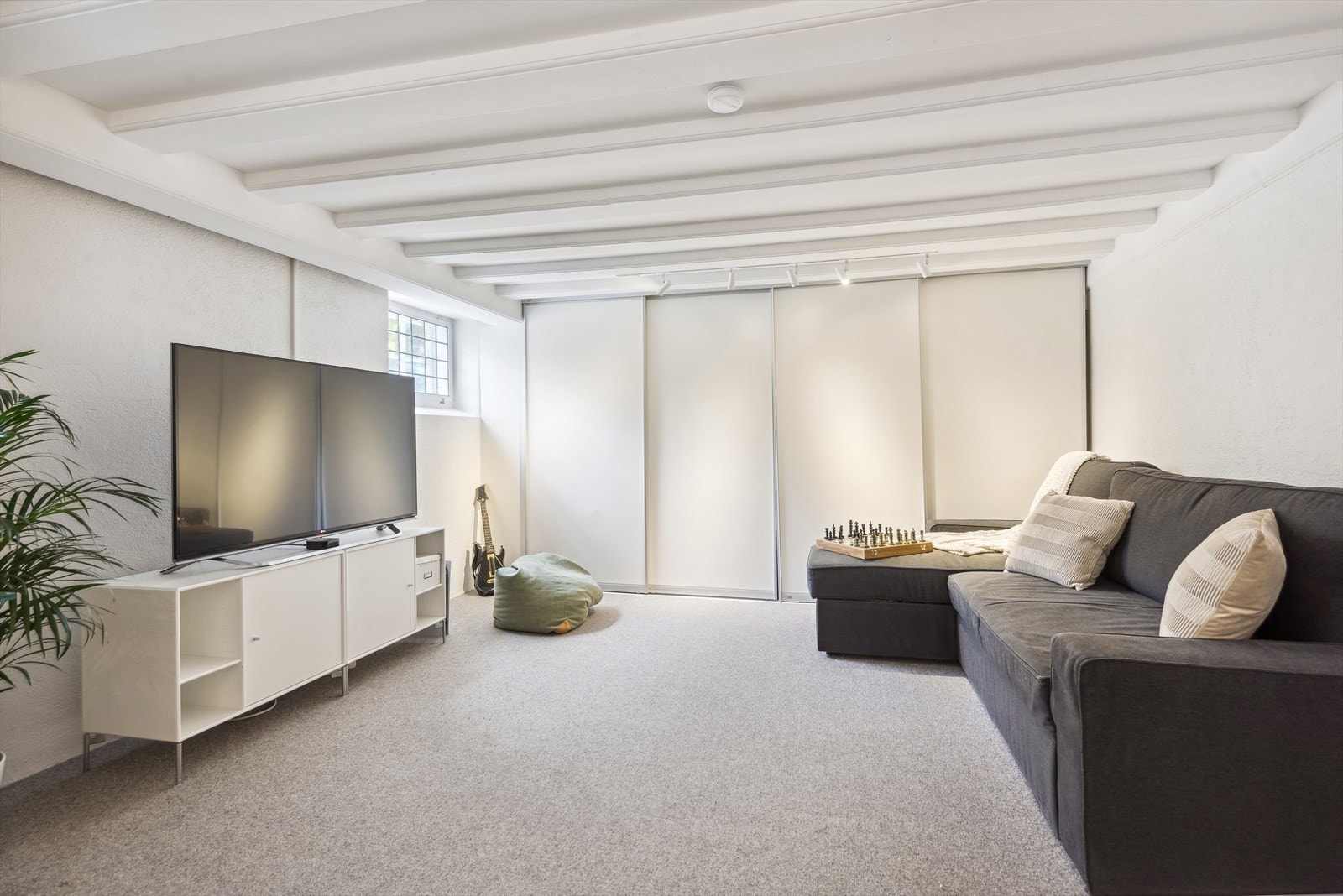 Praktisk kjellerstue/TV-stue med tepper på gulv. Galleribilde