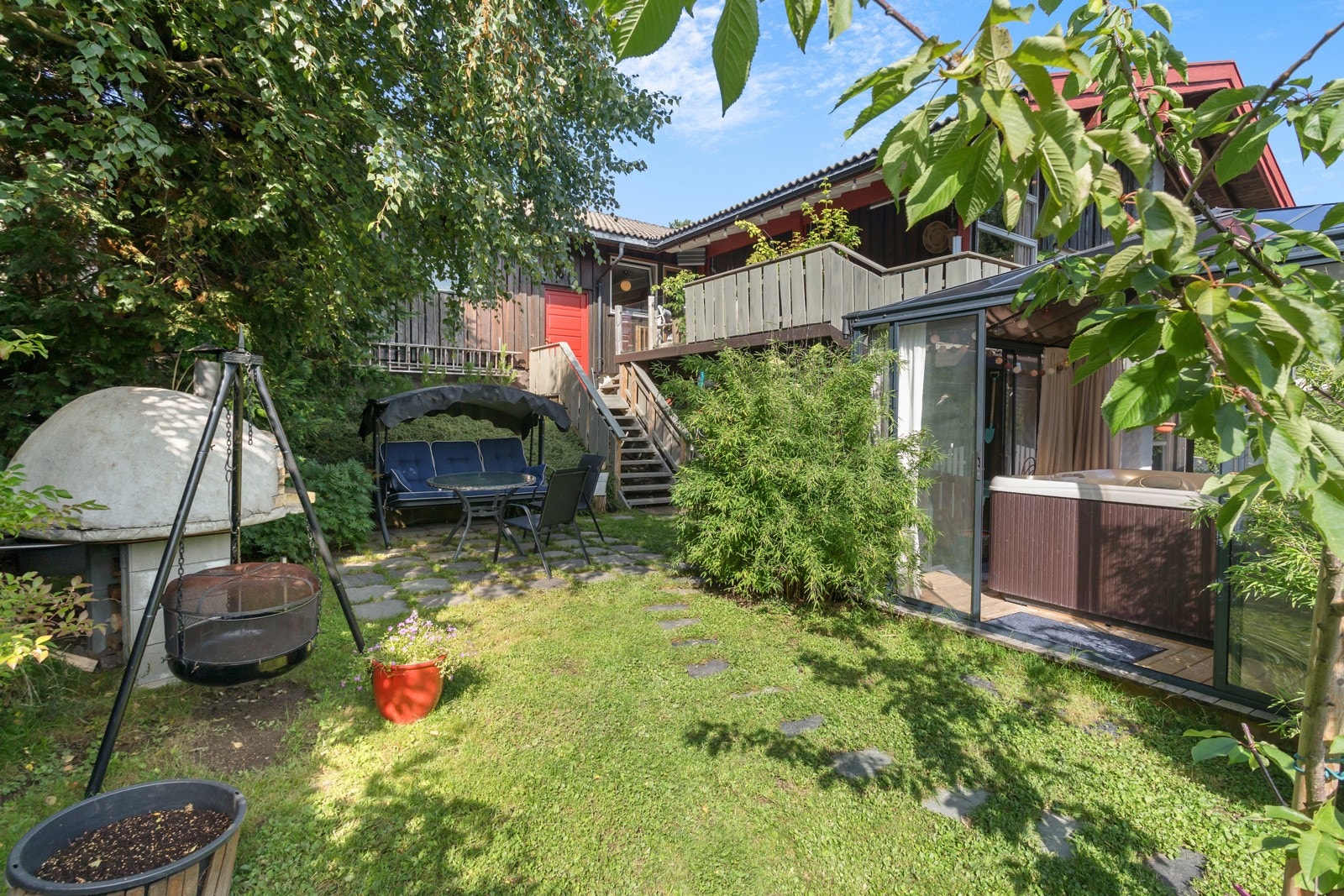 Verandaen leder videre ned og ut i hagen. Hagen er solrik og byr på blant annet en ny helårspaviljong med jacuzzi, spiseplass med plassbygget pizzaovn og dukkestue Galleribilde