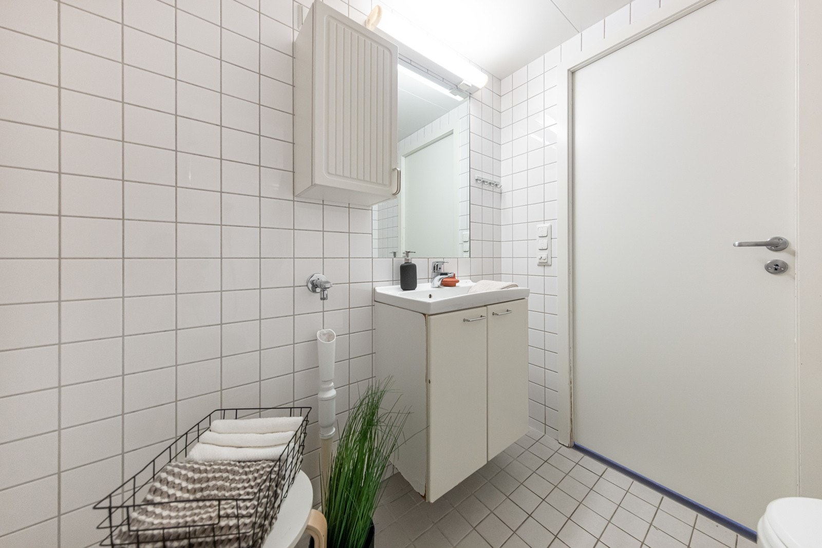 Baderom med skap for oppbevaring, speil m/ tilhørende lys, dusj, wc og opplegg for vaskemaskin. Galleribilde