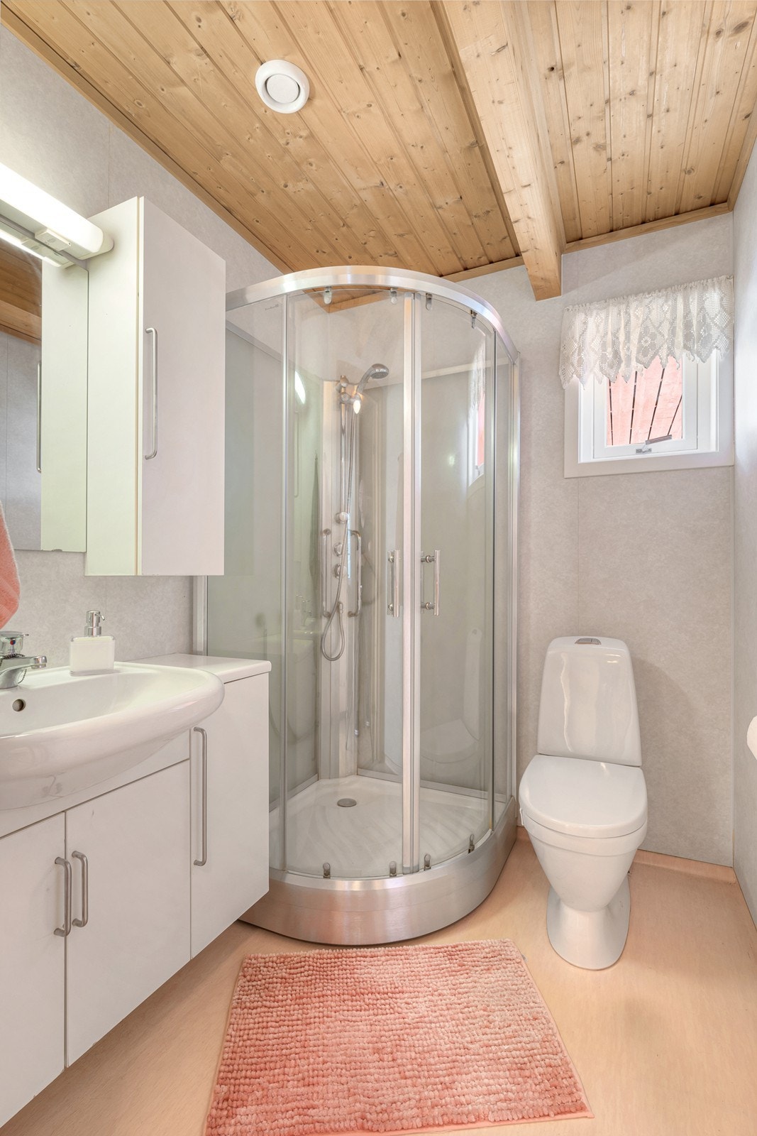 Det andre badet har heldekkende servant over underskap, veggskap, speil med belysning og dusjkabinett.
Begge badene har gulvfestet toalett. Galleribilde