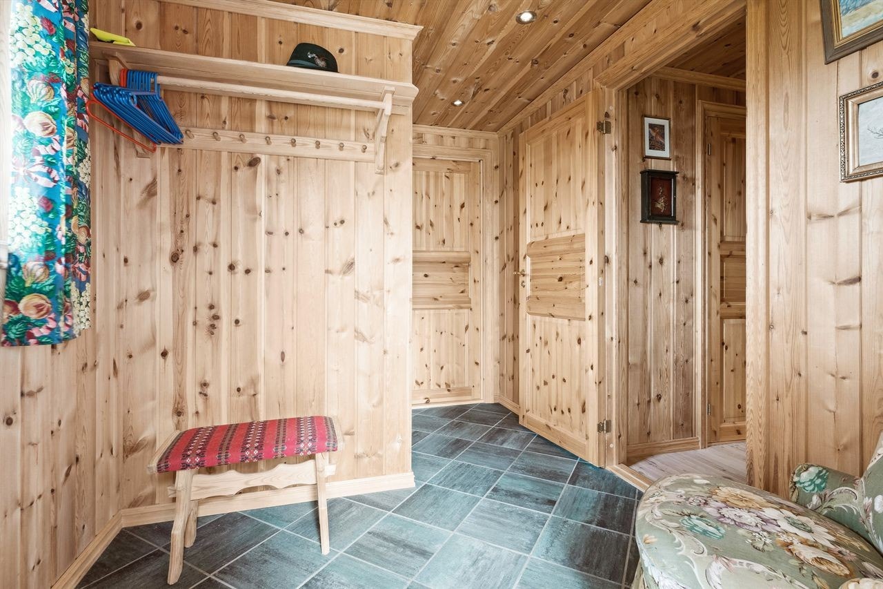 Her kommer man inn i en entré med panel på veggene, mørke fliser på gulvet og panel i himling. Galleribilde