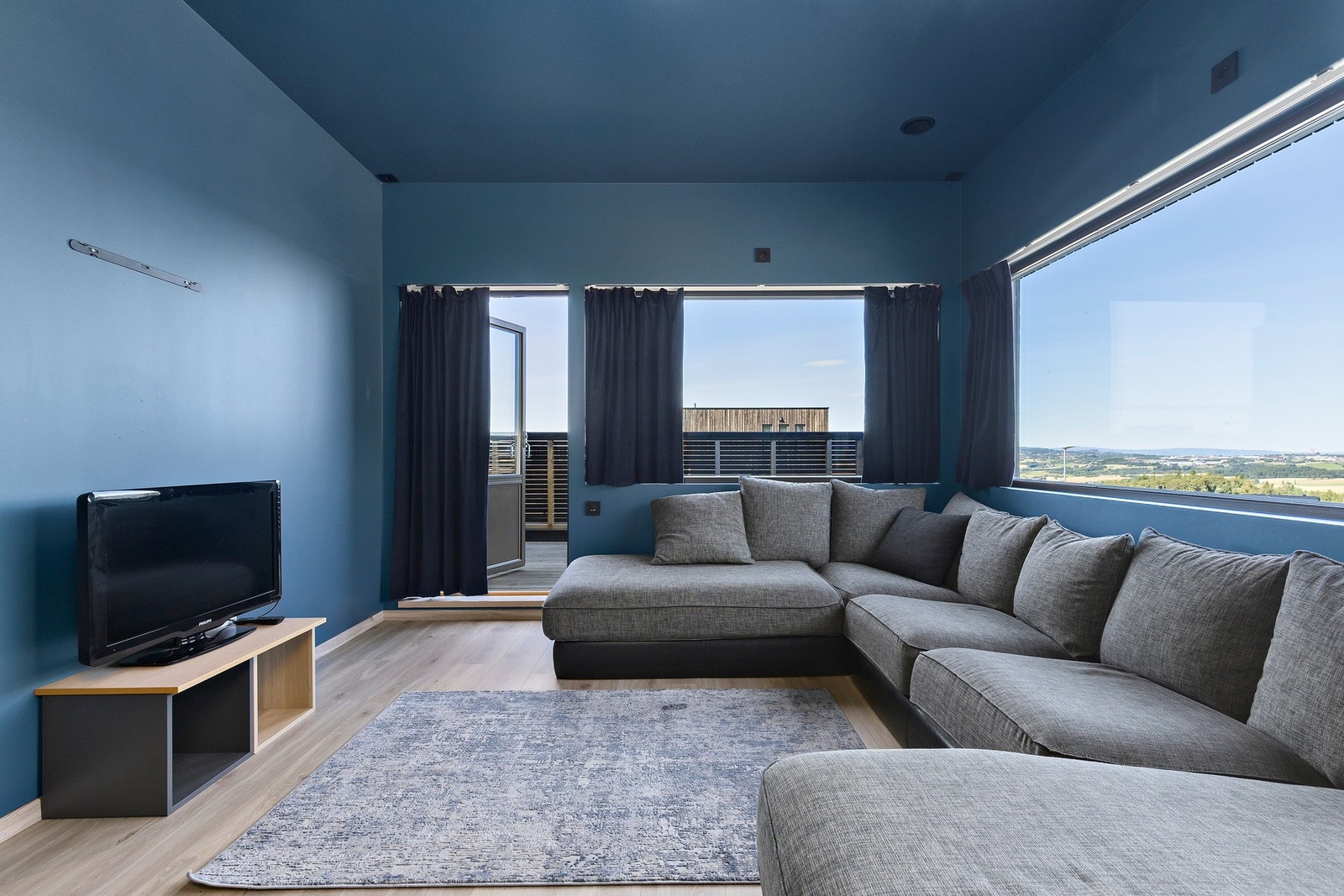 Fin tv-stue med store vindusflater og utgang til balkong Galleribilde