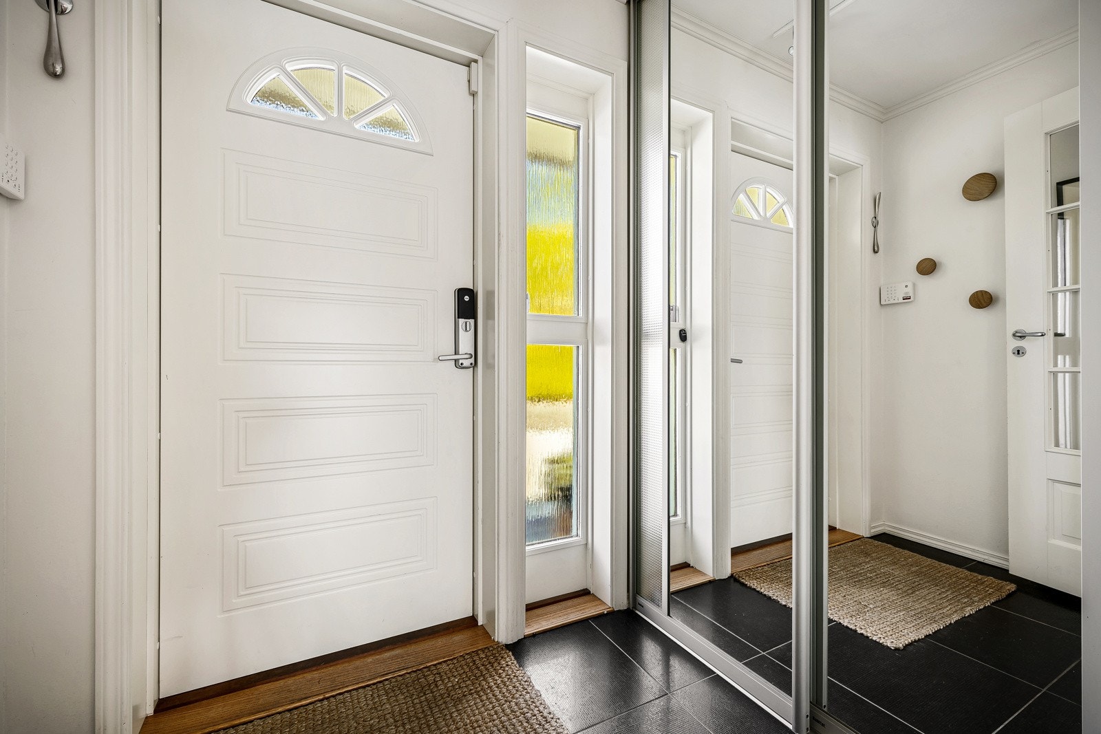 Entré med flislagt gulv med varmekabler og skyvedørsgarderobe med speilfronter. Galleribilde