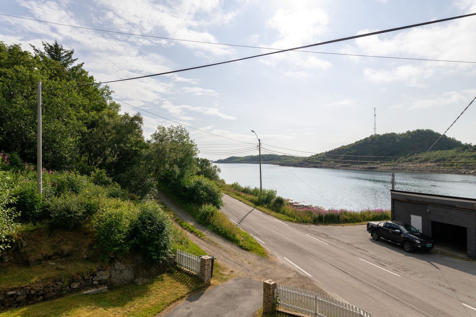 Det er asfaltert innkjørsel til boligen, med parkeringplasser og garasje på nedre side av veien. Galleribilde