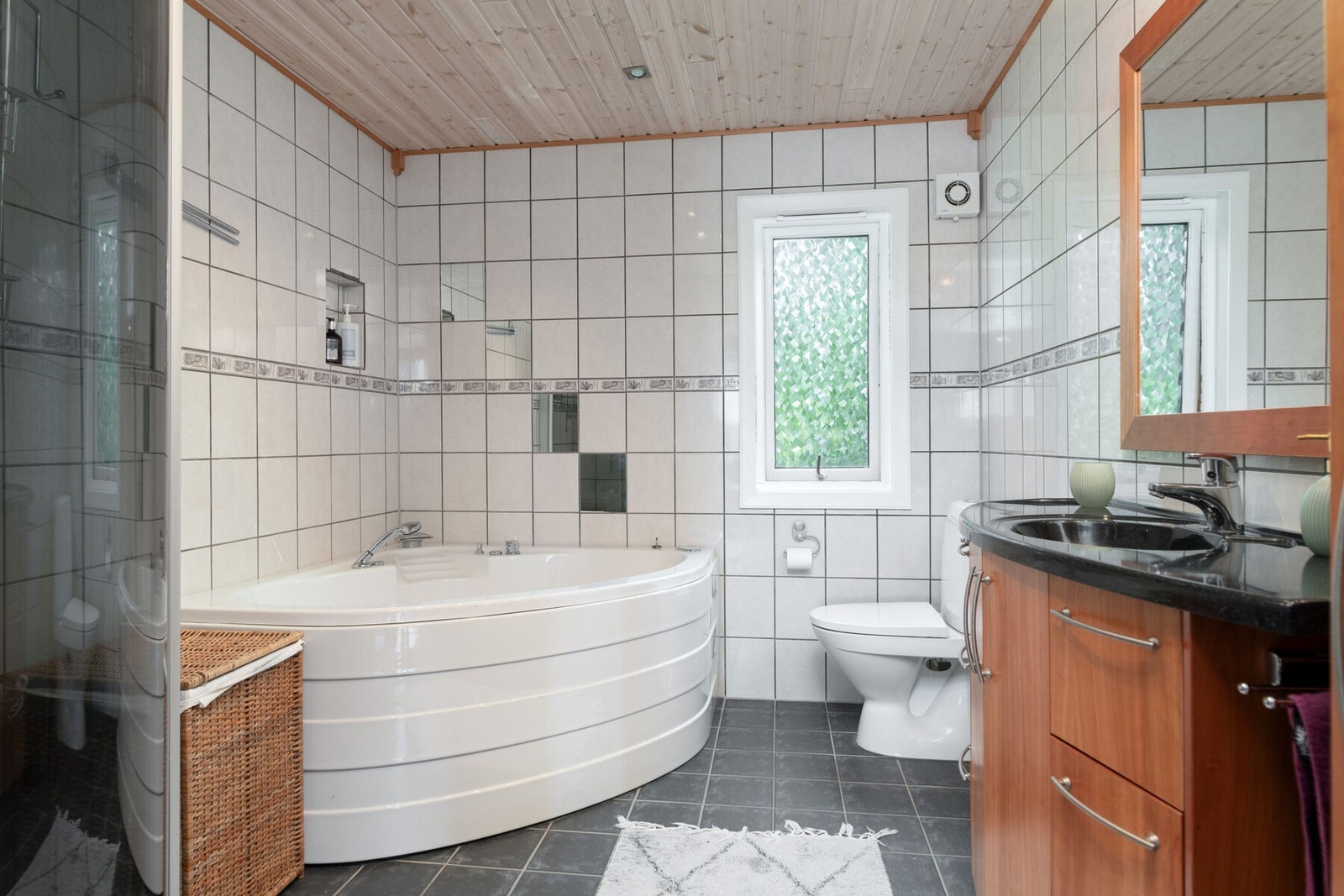 Badet er helfliset med spotbelysning i taket og varmekabler i gulvet. Innredet med dusj, badekar, toalett og servantmøbler. Galleribilde