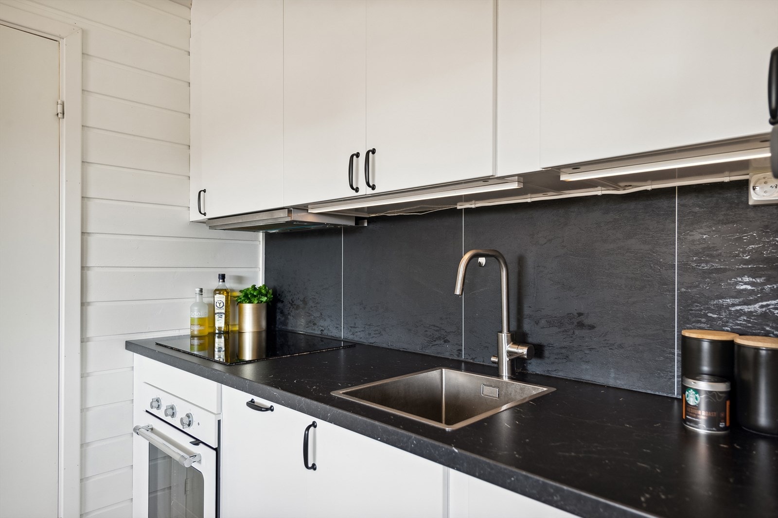 Kjøkkenventilator er montert over koketopp, med avtrekk ut. Galleribilde