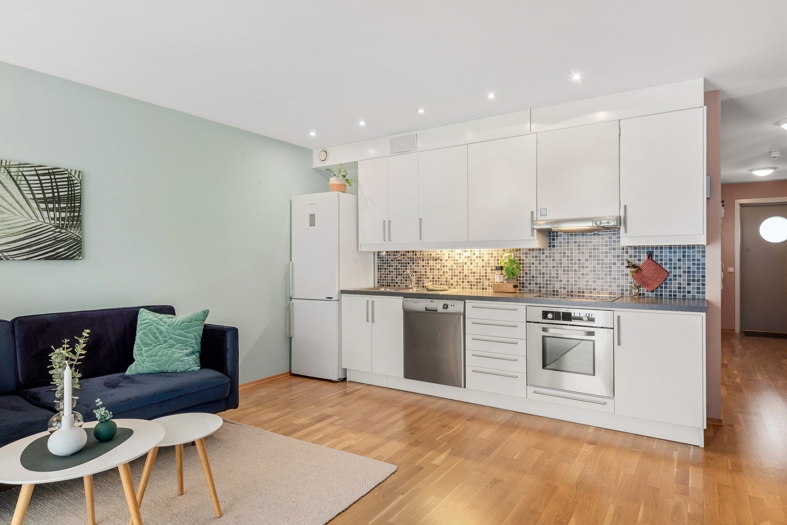 Kjøkkeninnredningen er moderne med lyse, slette fronter. En tøff vinyltapet mellom benk og overskap og downlights i tak langs
innredning gir kjøkkenet et moderne preg. Galleribilde