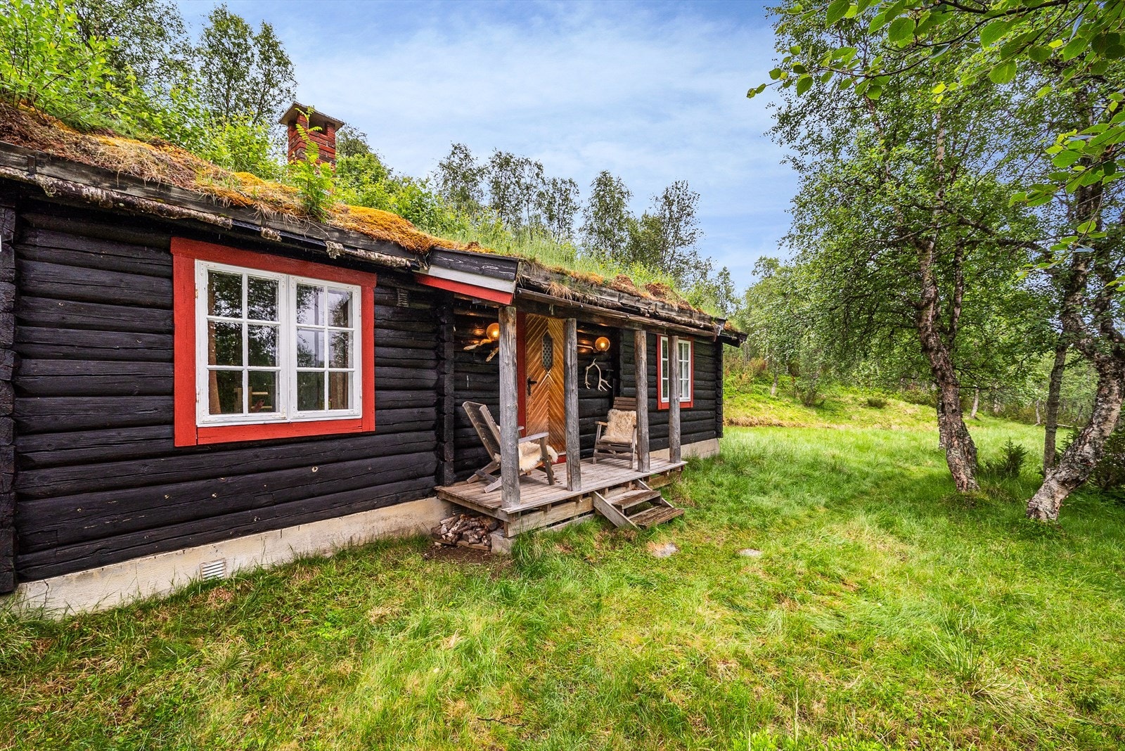 Hovedhytta er en tømmerhytte med saltak som er tekket med torv Galleribilde