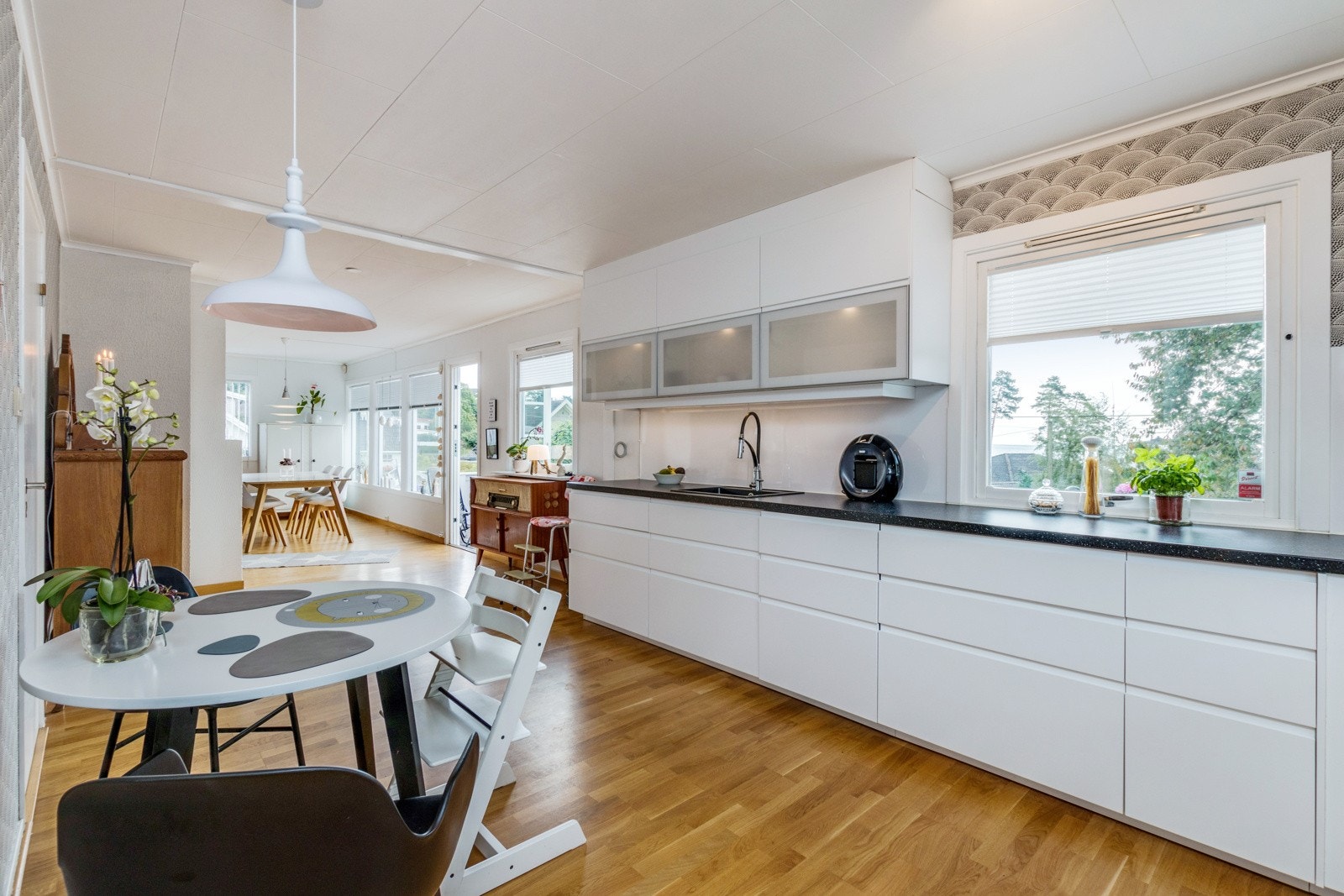 Lyst og flott kjøkken med hvite fronter og plass til frokostbord Galleribilde