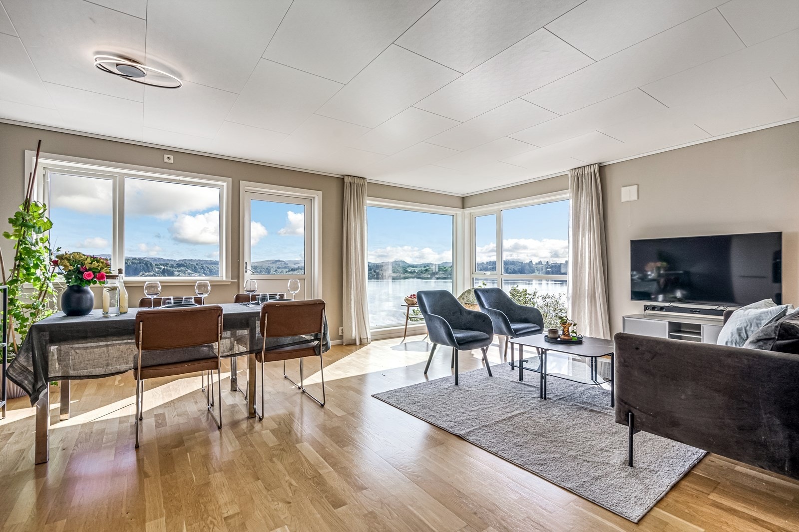 Stue med åpen løsning til kjøkken. Her kan en skue ut over fjorden og det vakre landskaper fra store deler av rommet. Galleribilde